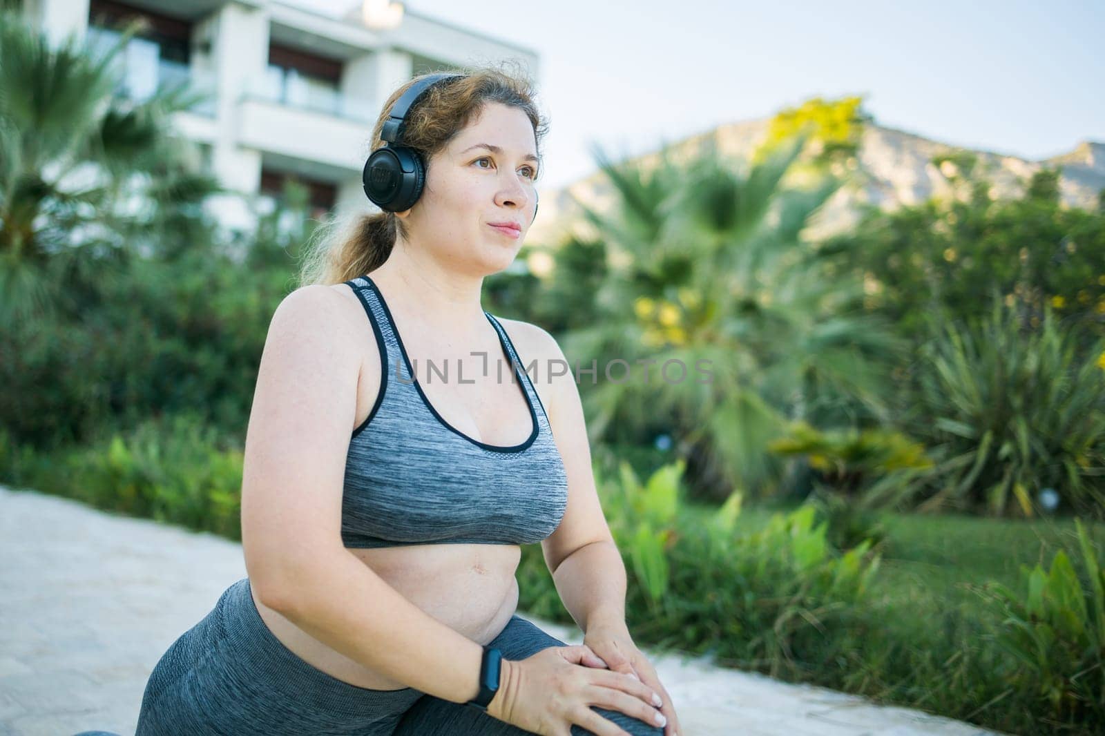 Young pretty smiling plus size woman in sporty top and leggings doing sport in summer outdoor