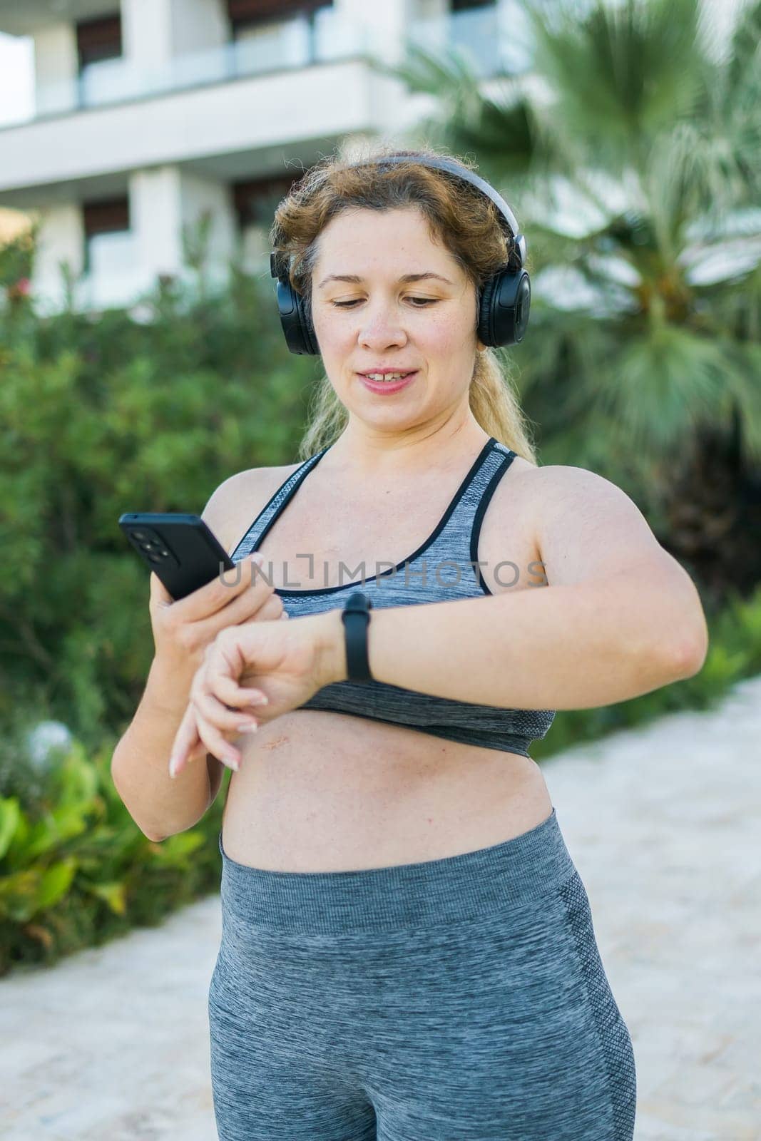 Fat woman checking time or heart rate from smart watch. Exercise or running outdoors for weight loss idea concept. Wellness and wellbeing body positivity by Satura86