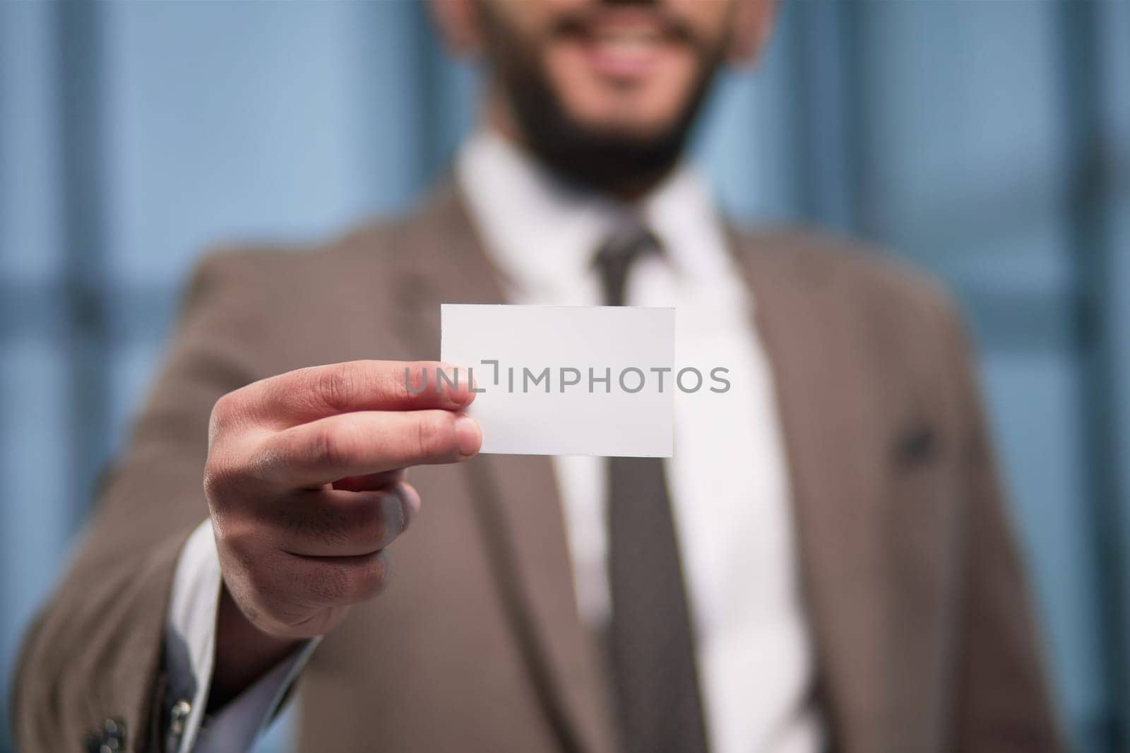 businessman with blank business card on office background
