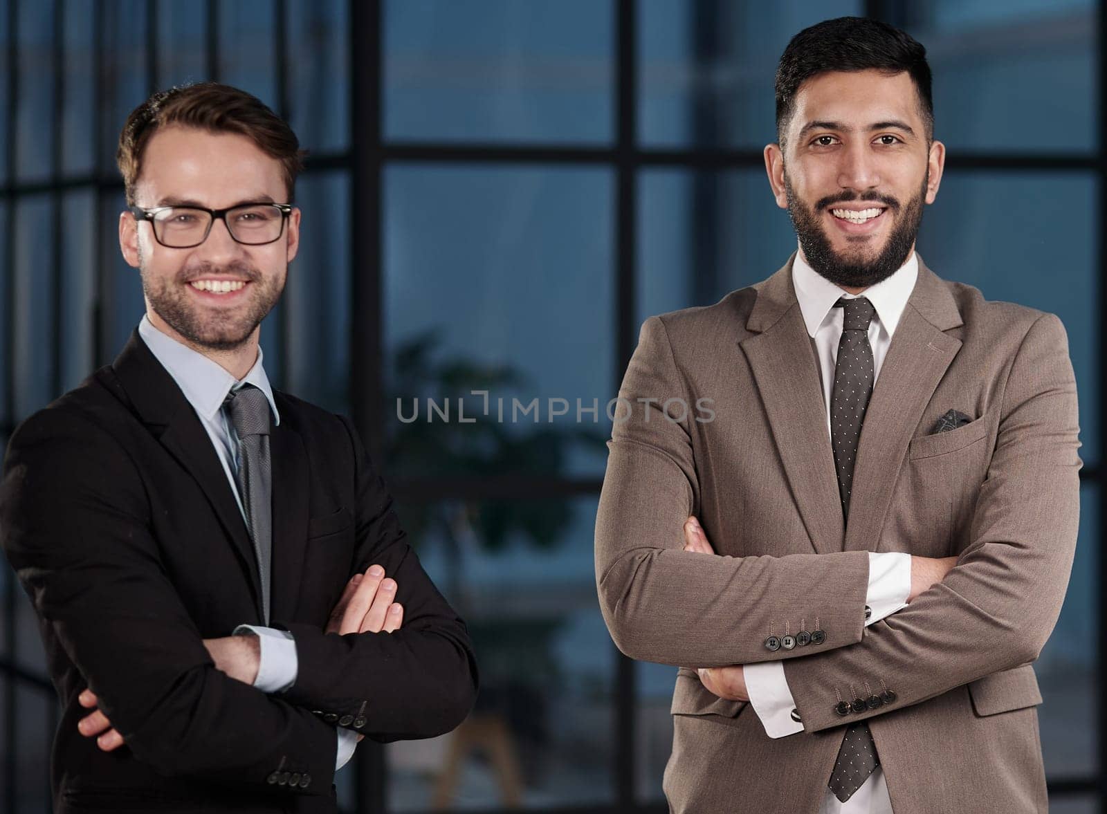 Portrait of two businesspeople standing together with their arms crossed in an office.