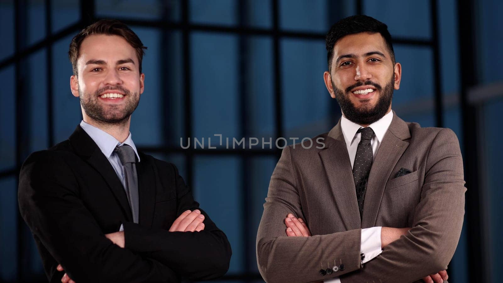 Two happy men standing with arms folded