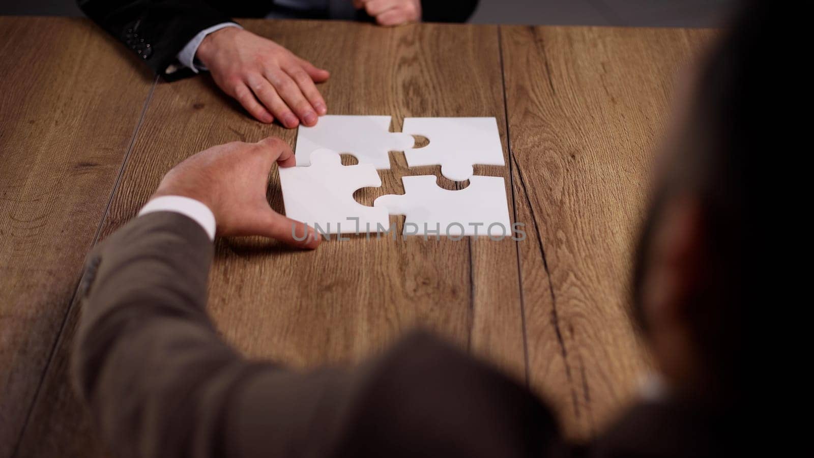 close up.business partners putting together a puzzle ,sitting at office Desk