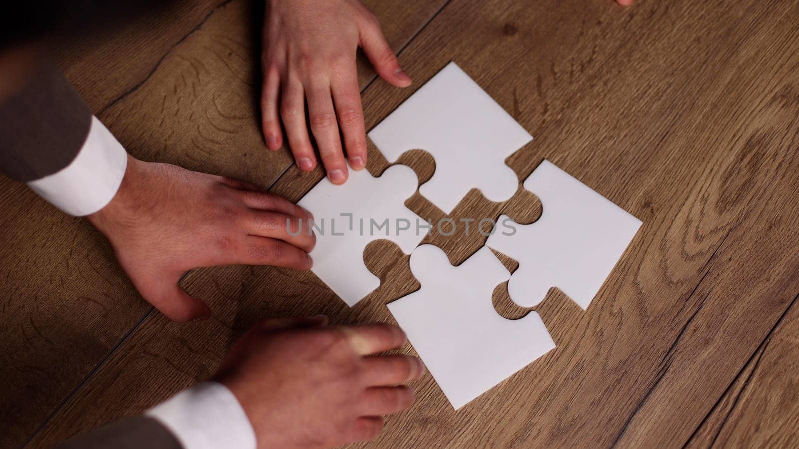 close up.business partners putting together a puzzle ,sitting at office Desk