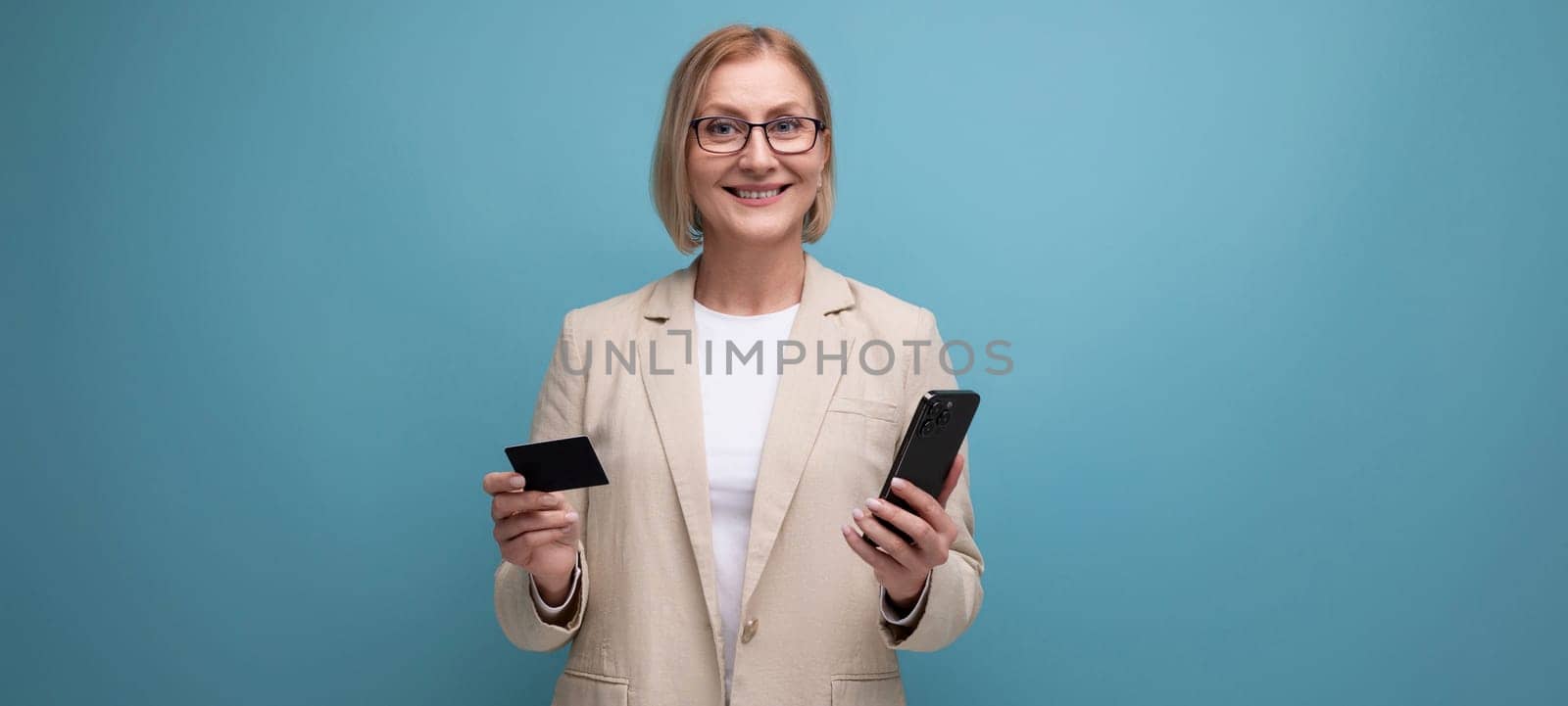 middle aged business woman holding credit card for online shopping on bright studio background with copy space.