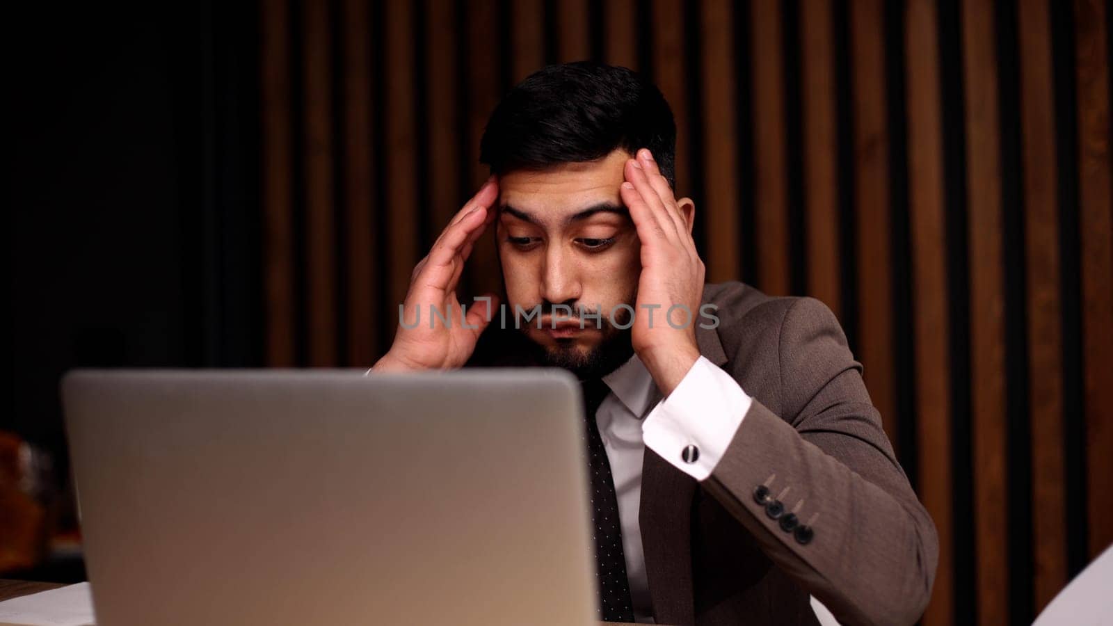 Tired man behind a computer screen from boring routine work in the office.