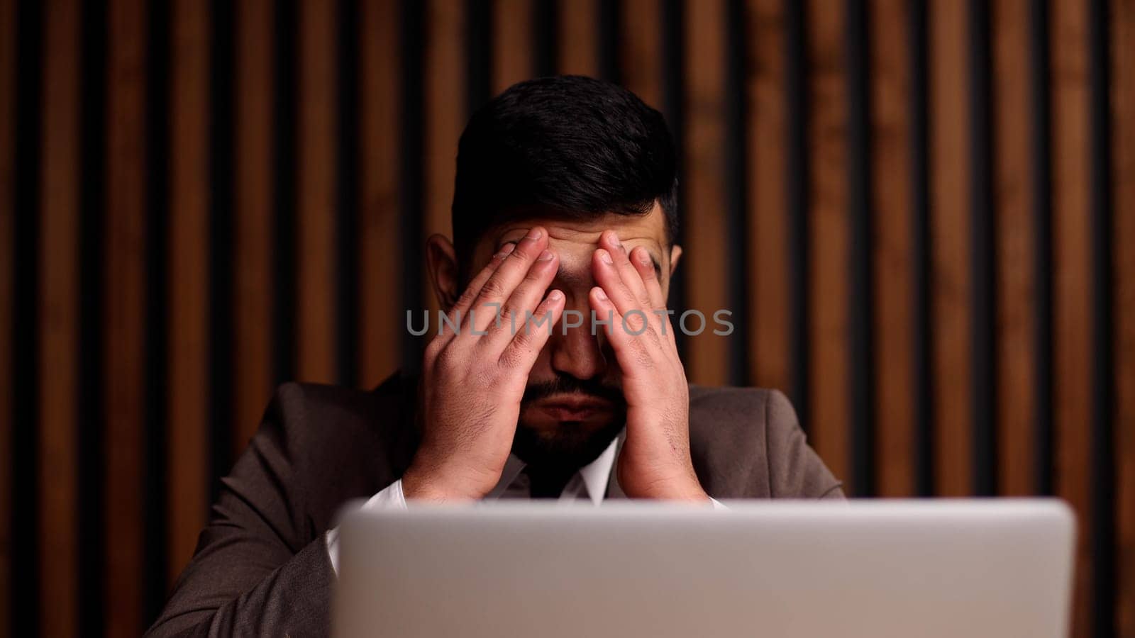 Tired man behind a computer screen from boring routine work in the office.