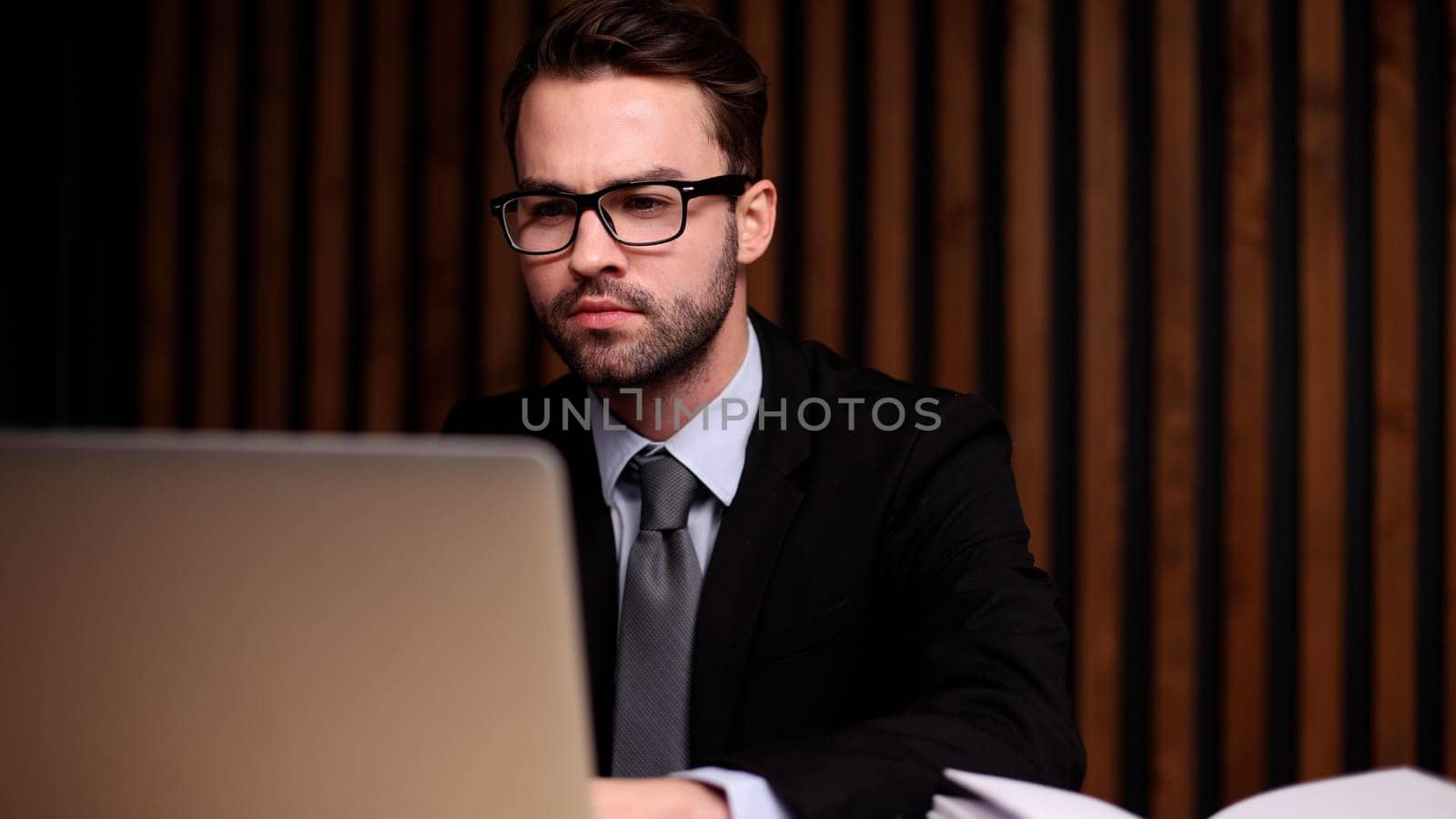 Shot of a young businessman using a computer at his desk in a modern office.