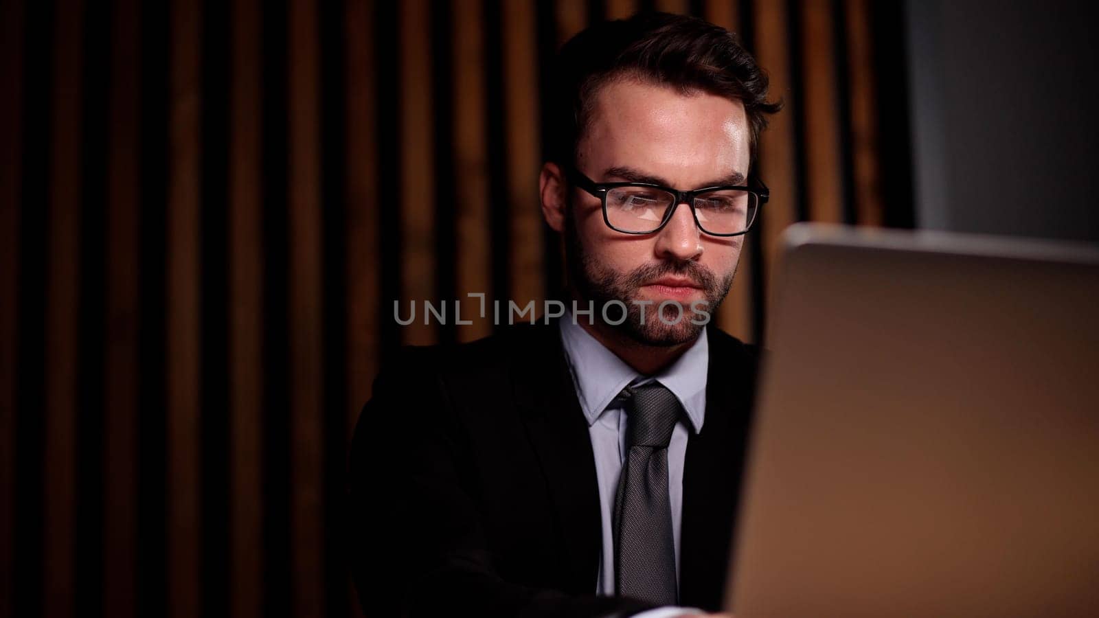 Shot of a young businessman using a computer at his desk in a modern office.