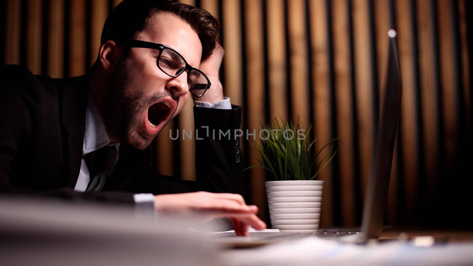 employee stretching and yawning during break in office after work done.