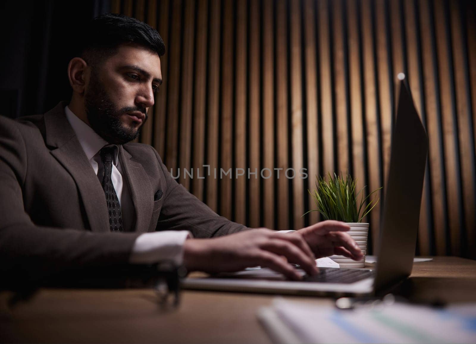 A man of Spanish appearance works at the office with a laptop