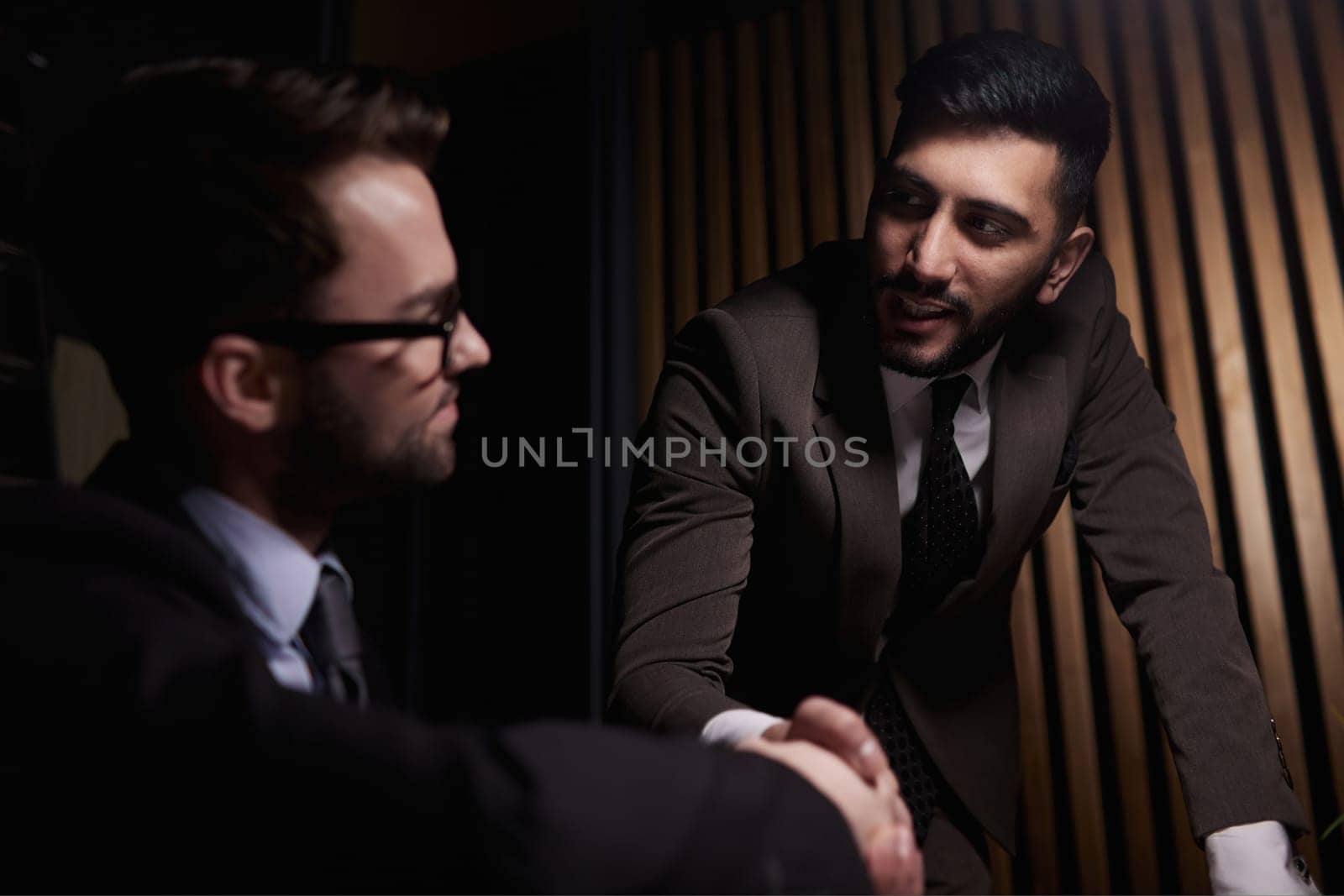 Two positive confident businessmen shaking hands over meeting table after negotiation, closing deal, contract, agreement, smiling.