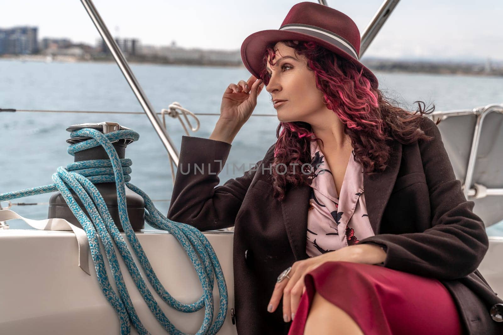 Attractive middle-aged woman at the helm of a yacht on a summer day. Luxury summer adventure, outdoor activities