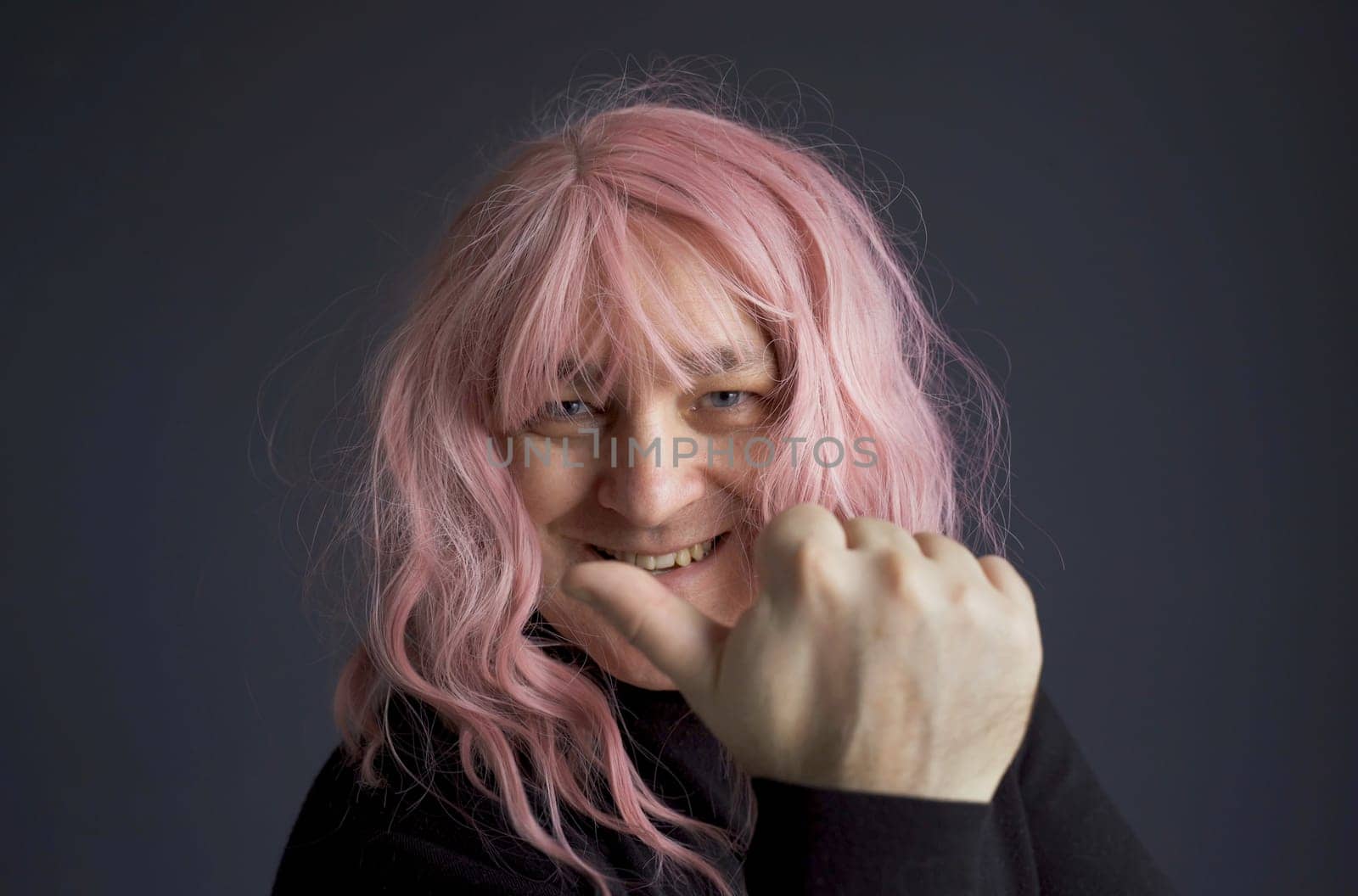 Portrait of a man in a pink wig, looking and pointing a finger to the side. close-up.