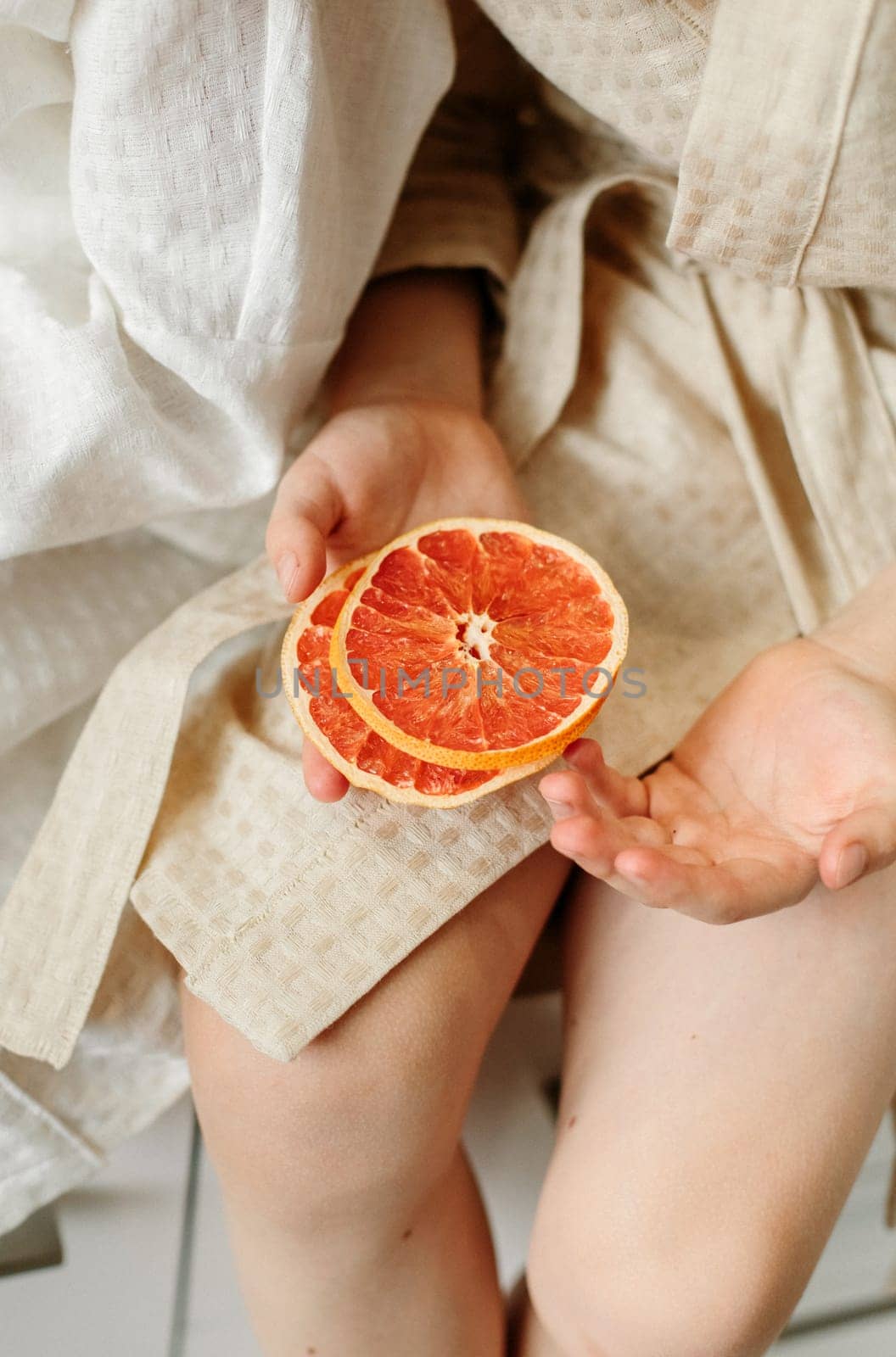 Candied oranges in the hands of a child. Close-up, vertical frame.