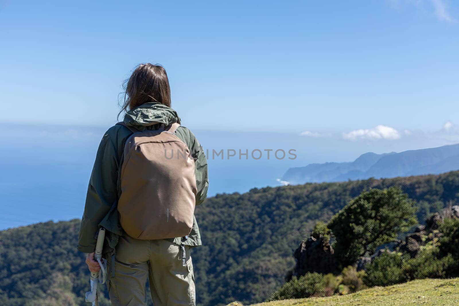 A woman with a backpack taking in the majestic view of a coastal landscape