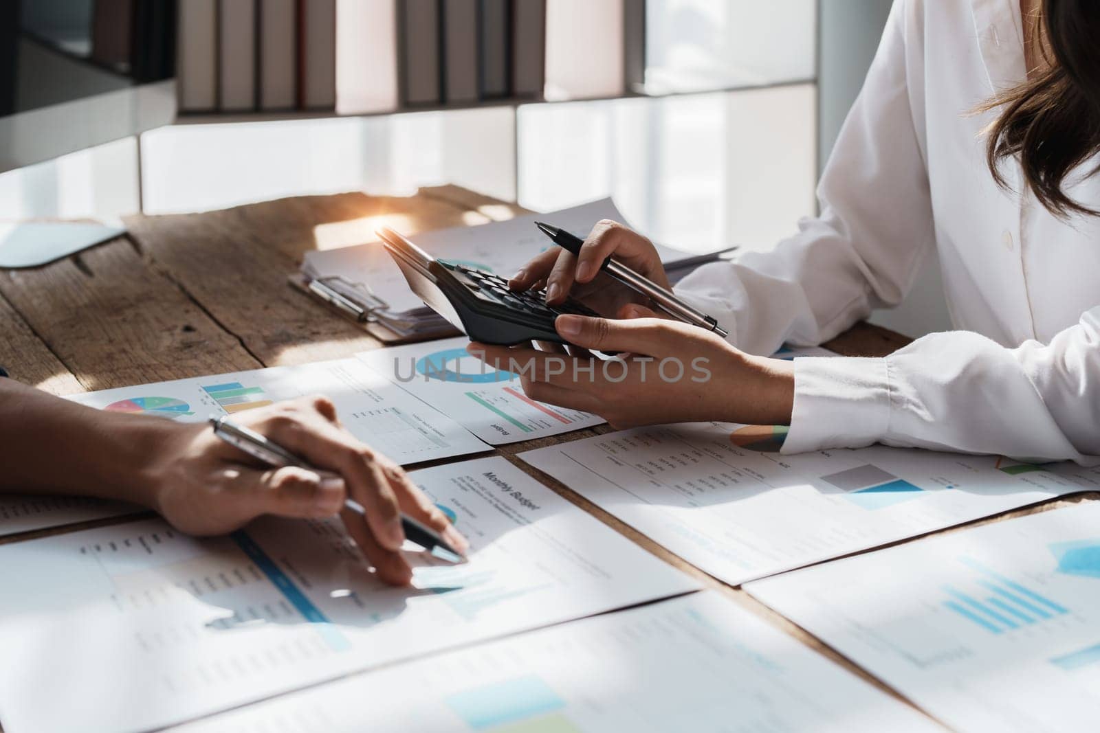 Accountant checking financial statement or counting by calculator income for tax form, Business woman sitting and working with colleague discussing the desk in office. Audit concept.