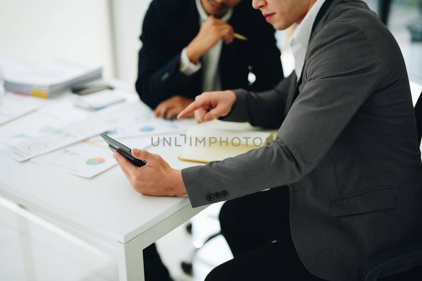 Two business men meeting to talking or discuss marketing work in workplace using paperwork, calculator, computer to work. by Manastrong