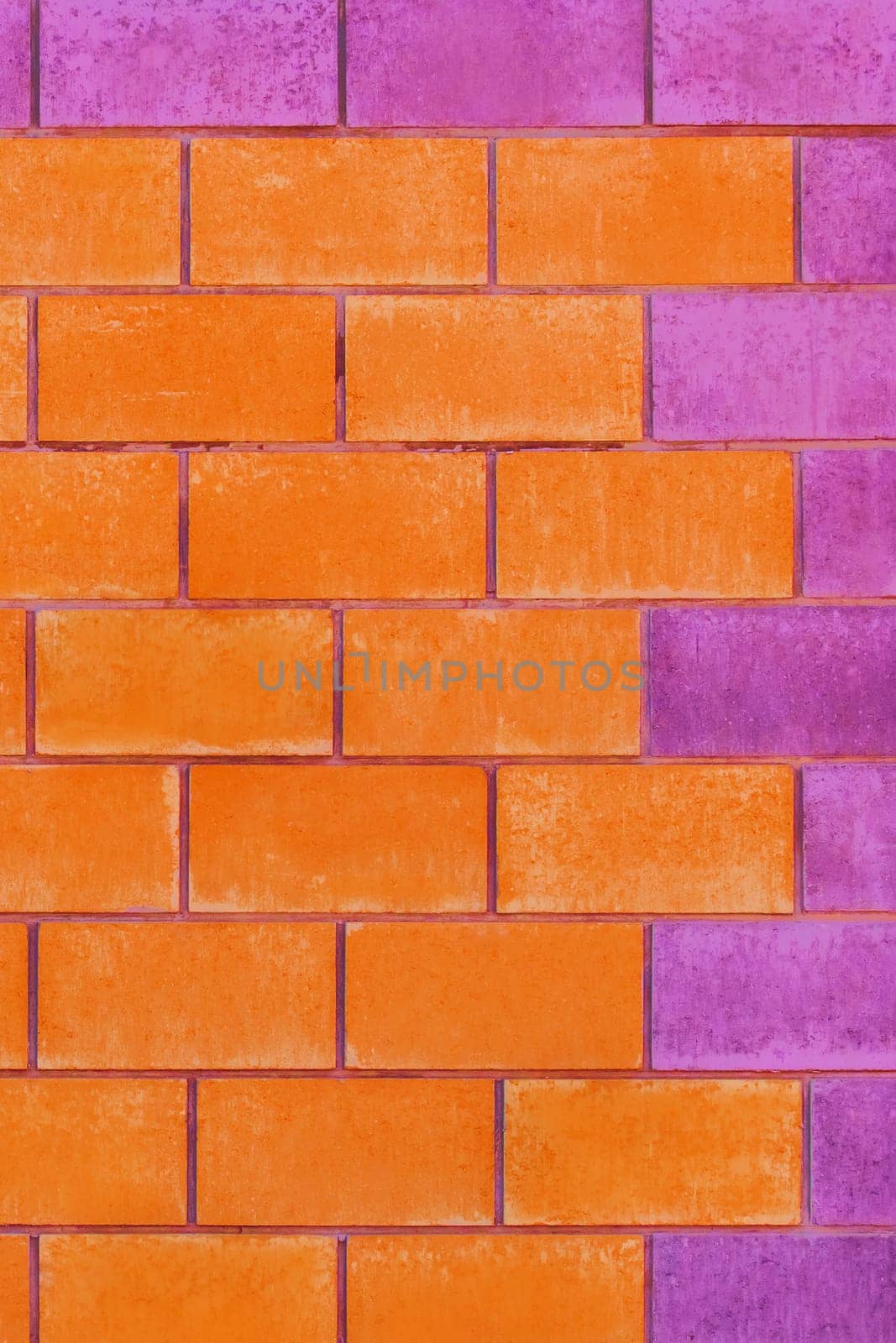 Orange and purple paint on brick blocks urban color vibrant design wall texture background architecture.