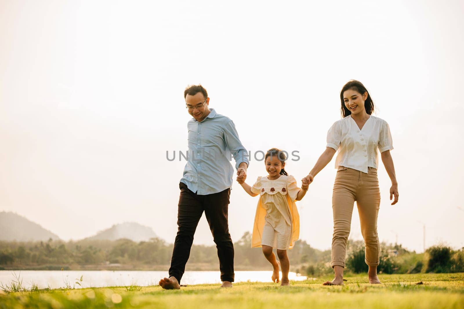 Asian family walking and holding hands in a beautiful countryside on a sunny day, feeling the love and the beauty of nature, Happy family day