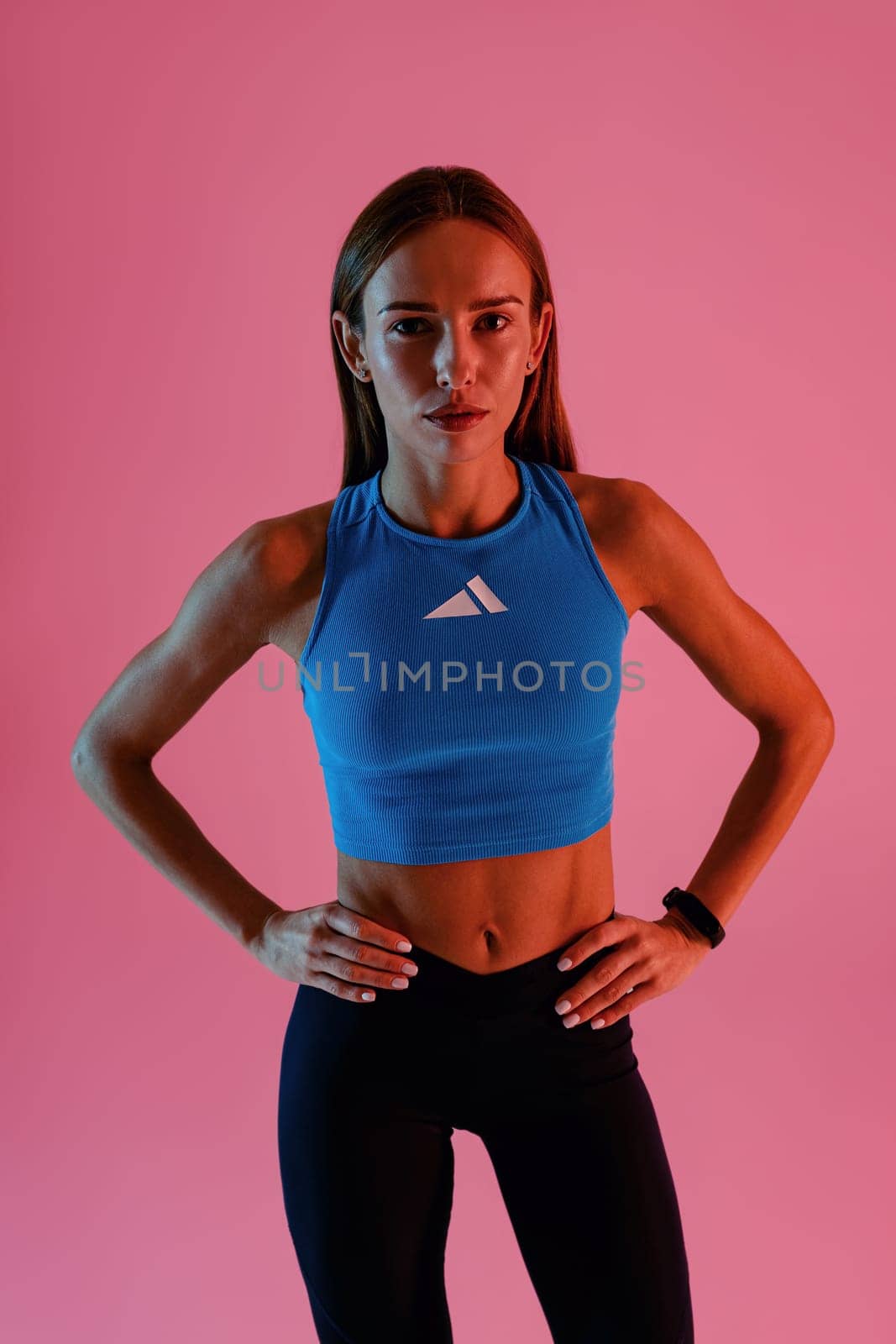Attractive fitness woman wearing sportswear posing over studio background and looking at camera by Yaroslav_astakhov