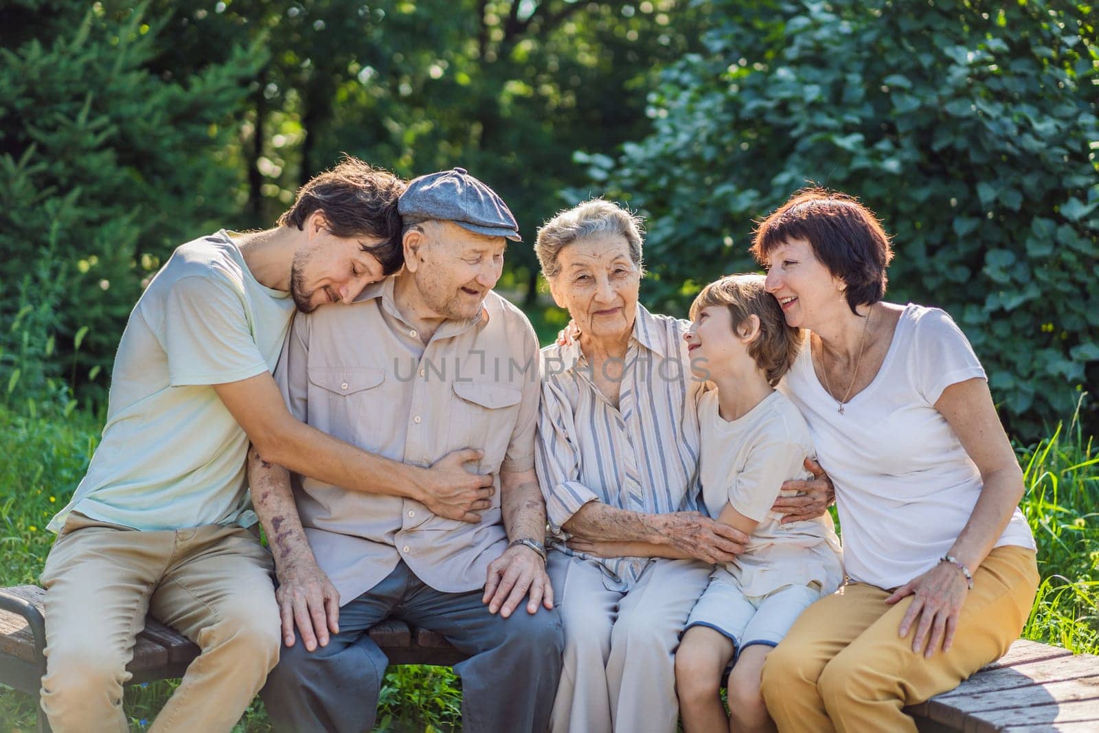 Four generations of family spend time together in the park. Elderly couple. Senior husband and wife holding hands and bonding with true emotions.