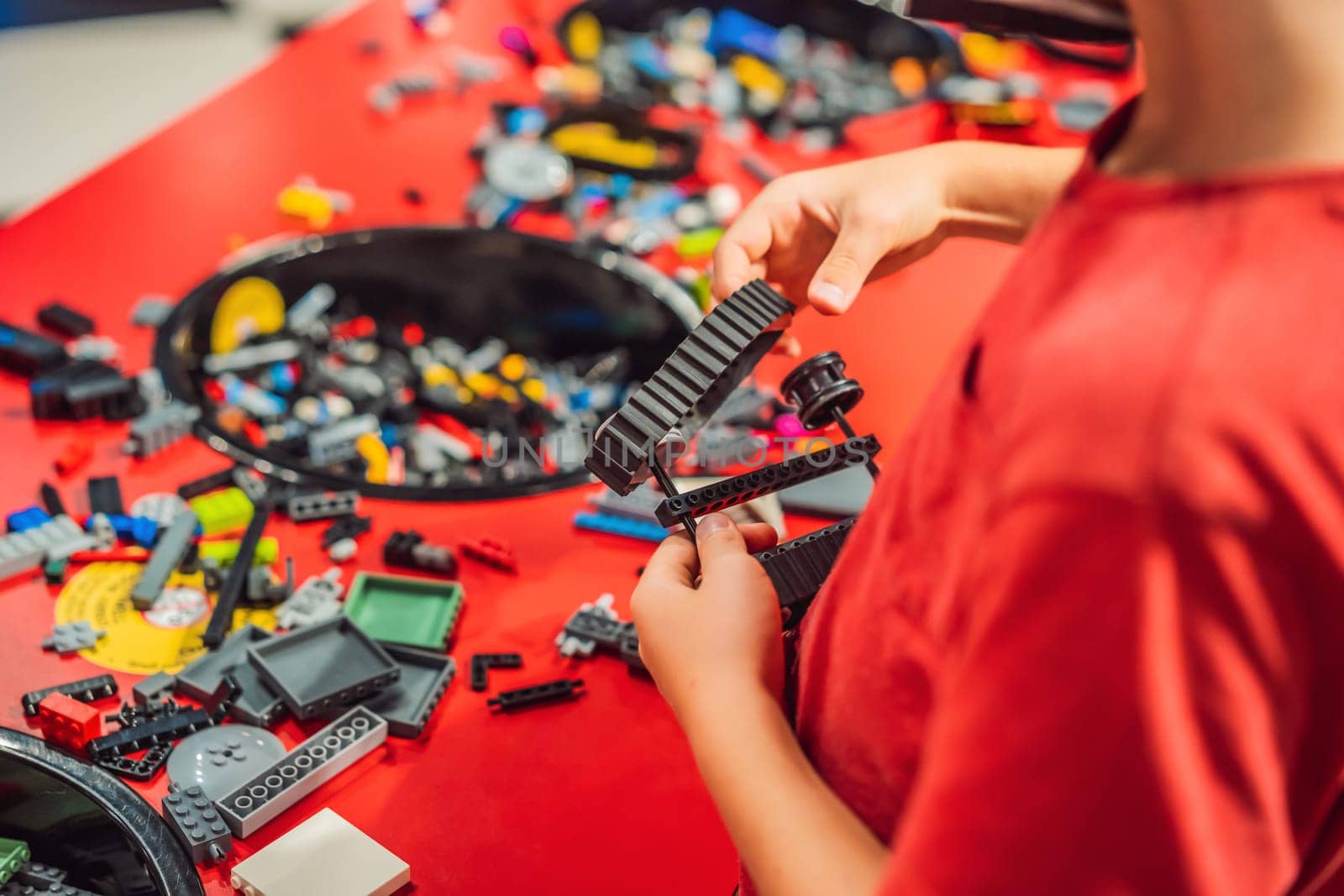 A boy in a medical mask plays with a constructor. child playing and building with colorful plastic bricks table. Early learning and development.
