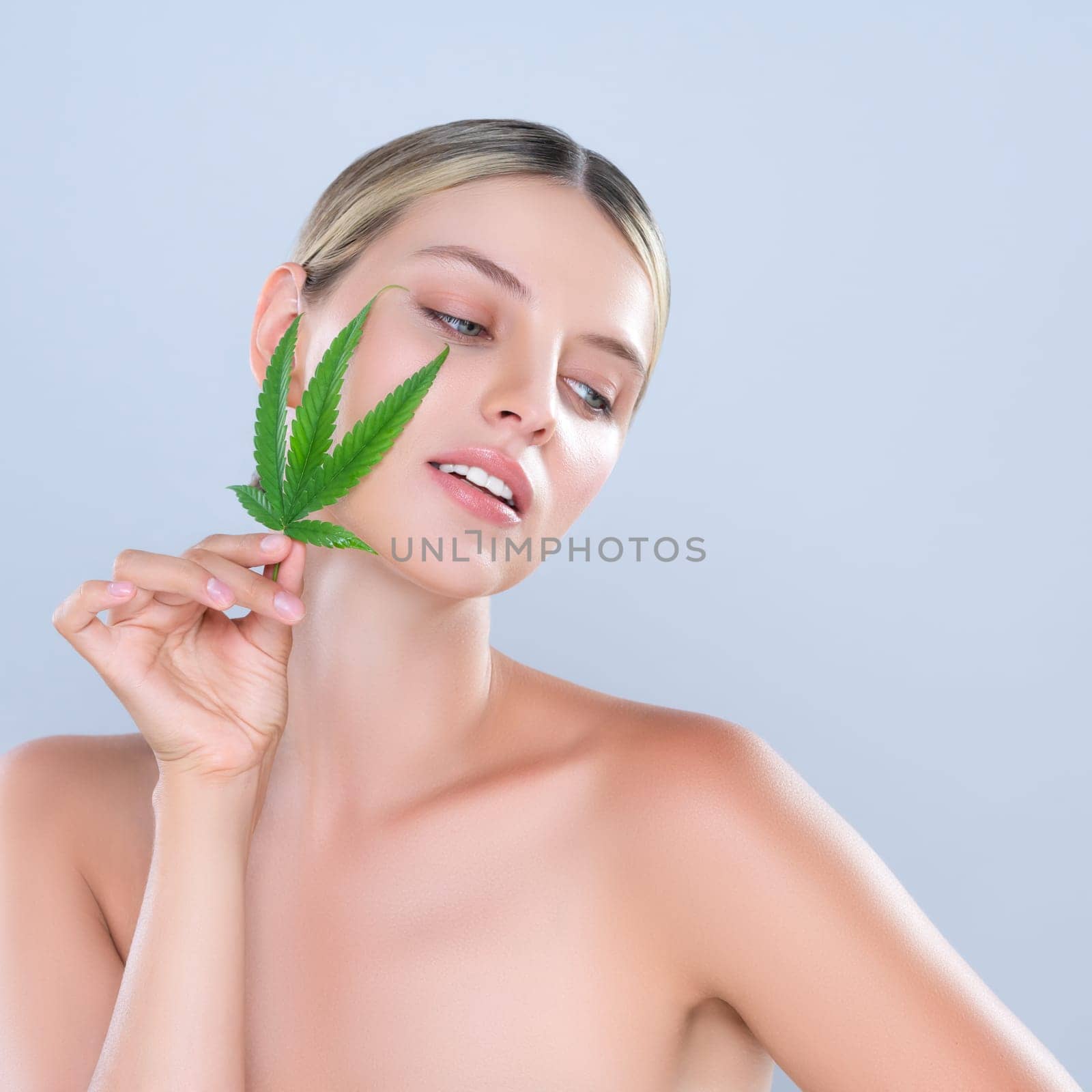 Alluring beautiful woman model portrait holding green leaf as concept for cannabis skincare cosmetic product for skin freshness treatment in isolated background.