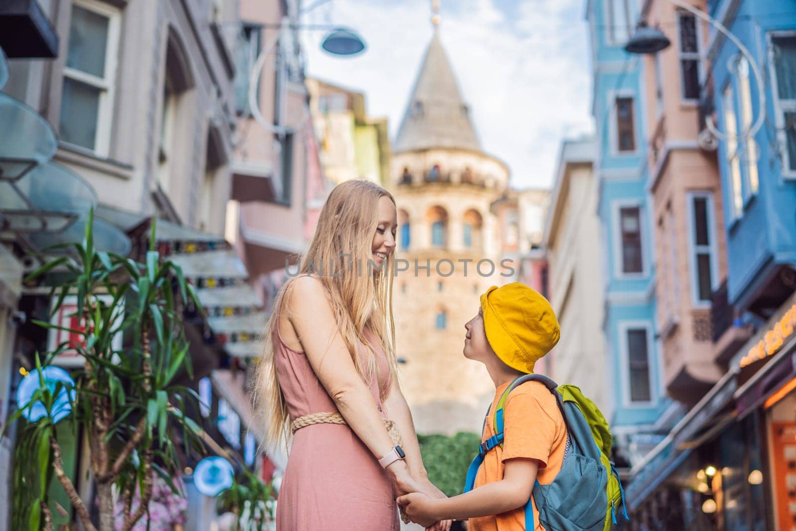 Portrait of beautiful mother and son tourists with view of Galata tower in Beyoglu, Istanbul, Turkey. Turkiye. Traveling with kids concept.