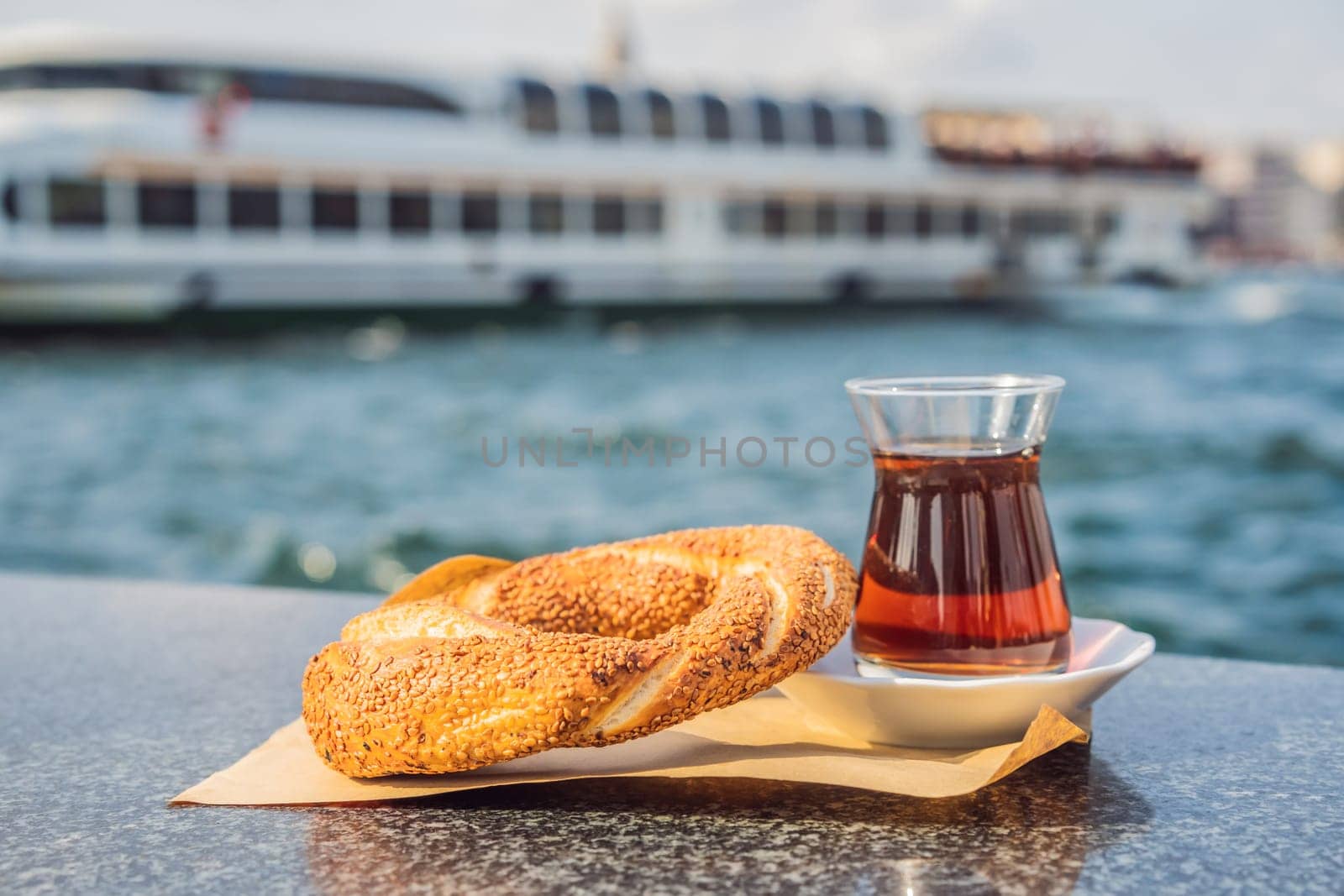 A glass of Turkish tea and bagel Simit against golden horn bay in Istanbul, Turkey. Turkiye by galitskaya