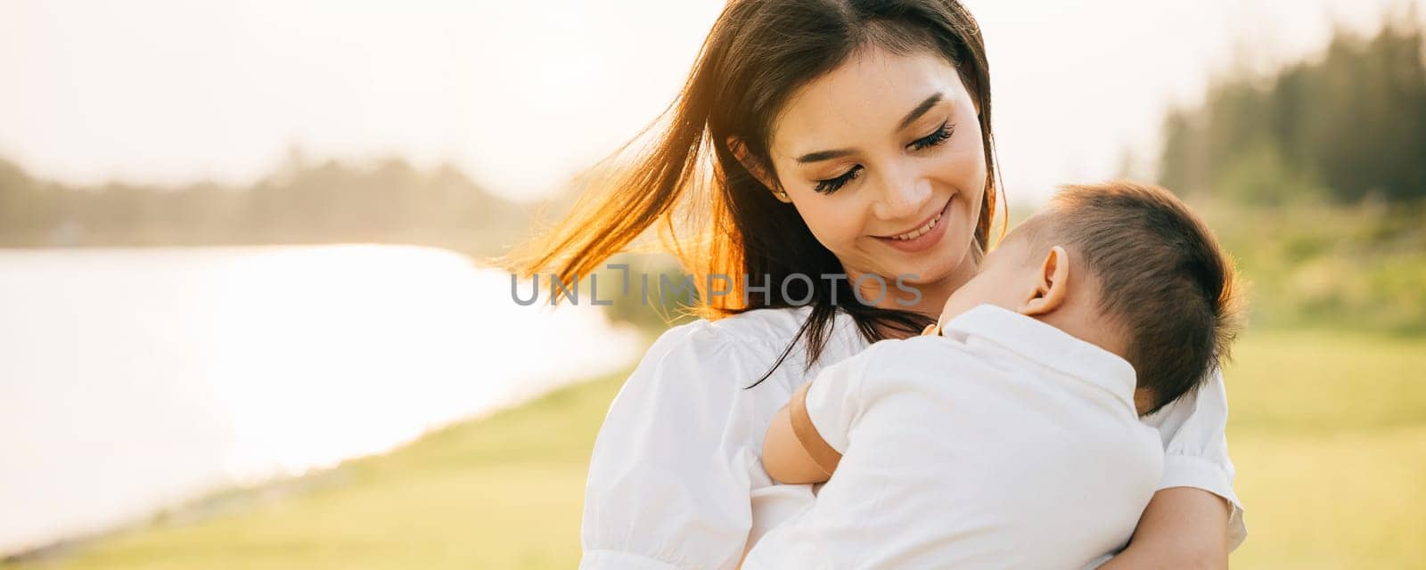 An intimate portrait of mother holding her sleeping baby in park at twilight. She smiles with pure joy, savoring tranquil moment in nature with newborn. heartwarming depiction of family care and love