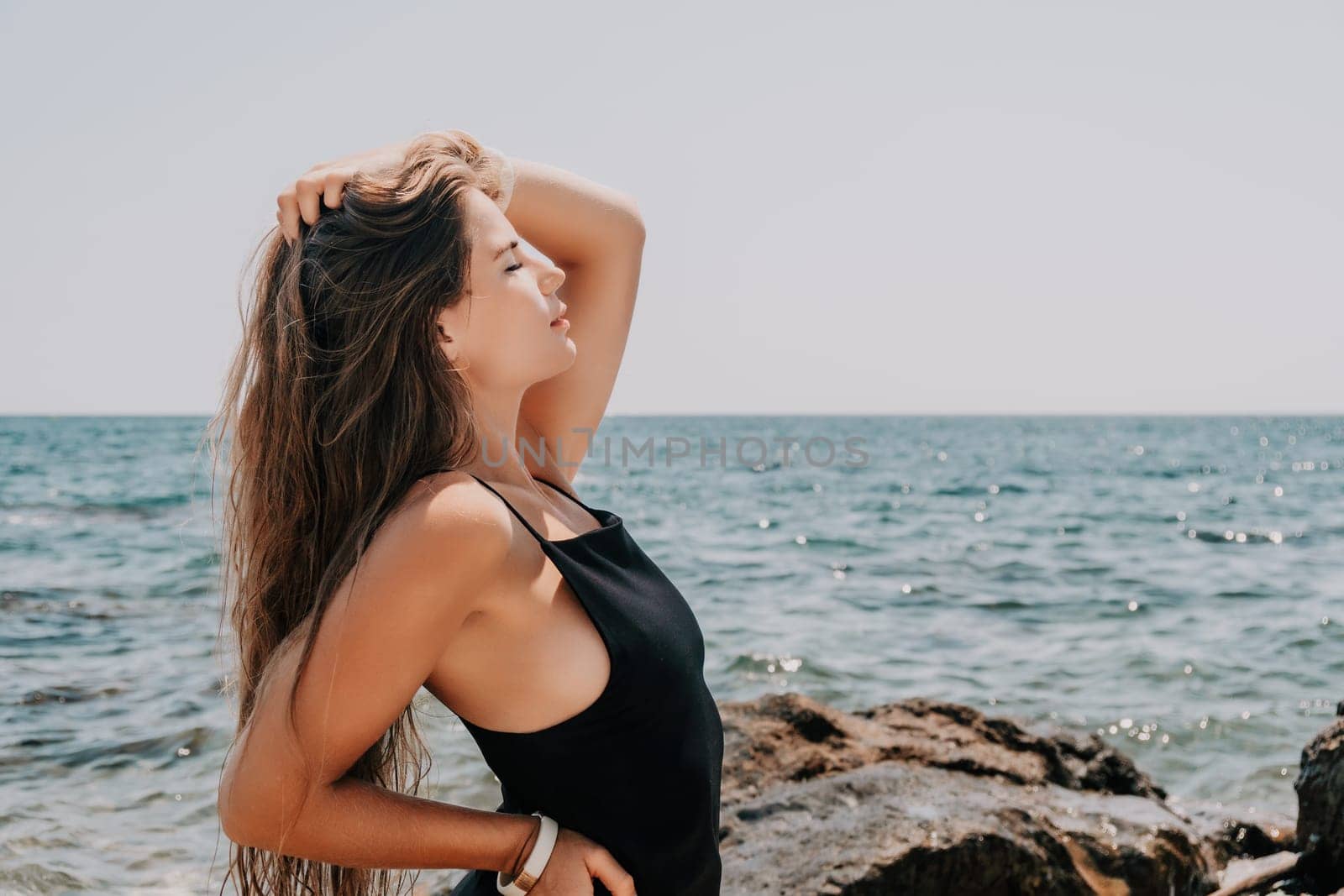 Woman summer travel sea. Happy tourist in hat enjoy taking picture outdoors for memories. Woman traveler posing on the beach at sea surrounded by volcanic mountains, sharing travel adventure journey by panophotograph