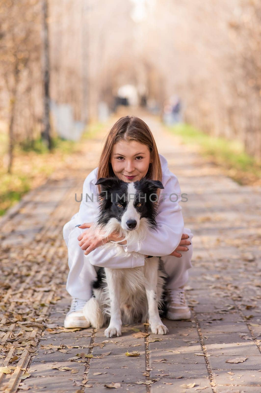 Caucasian woman hugging border collie in autumn park. Portrait of a girl with a dog. by mrwed54