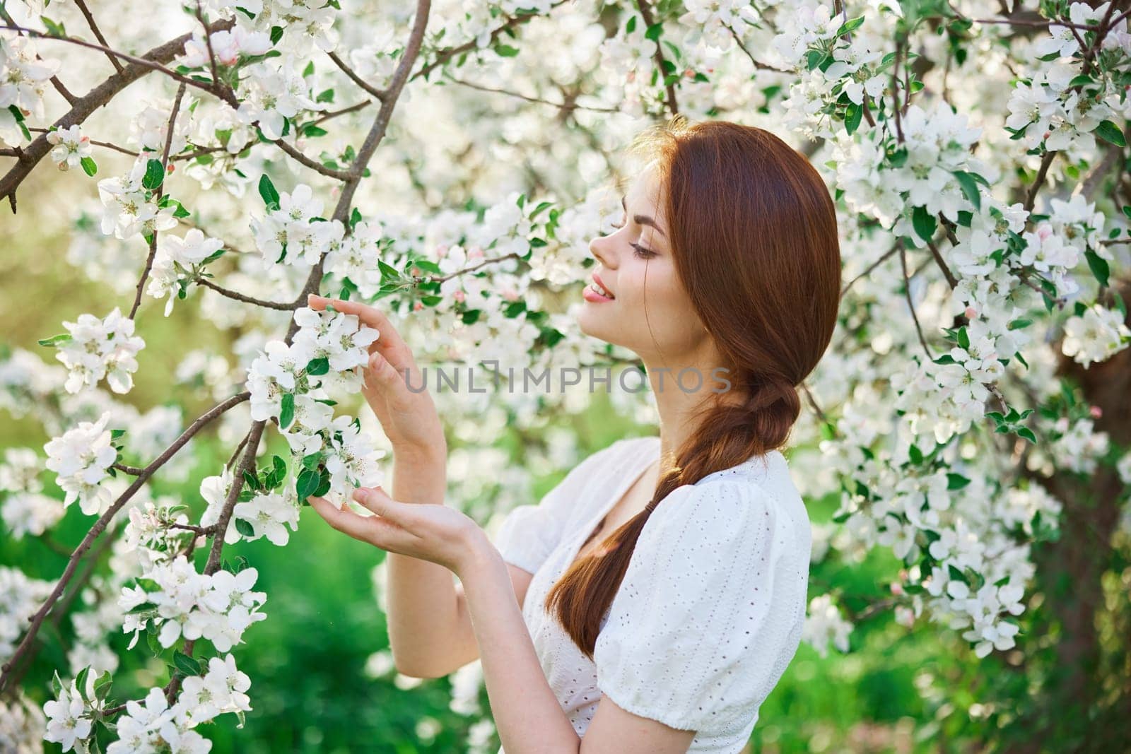 beautiful, cute woman touching flowers on a tree in the garden. High quality photo