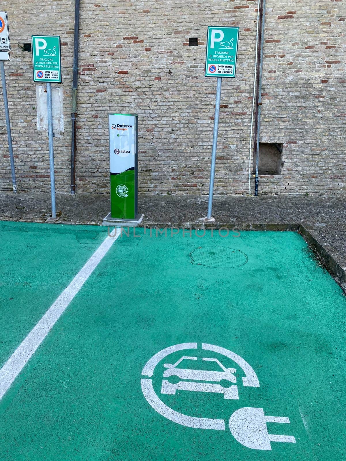 Loreto, Ancona, Italy - April 2023 Charging station for electric vehicles near the walls of Basilica sign and parking space for 2 cars