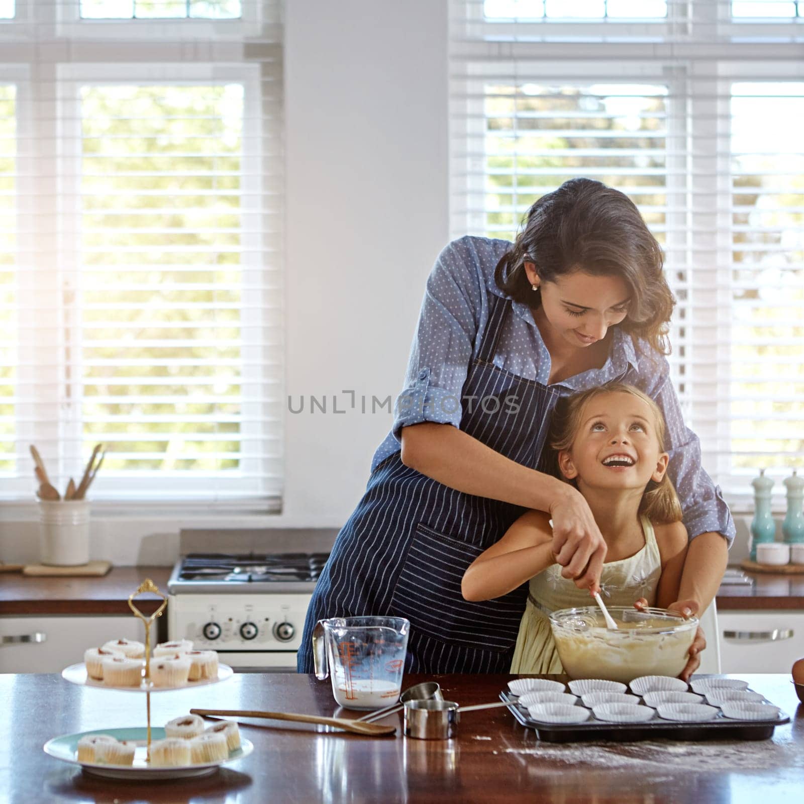 Let me help you my cupcake. a mother and her daughter baking in the kitchen. by YuriArcurs