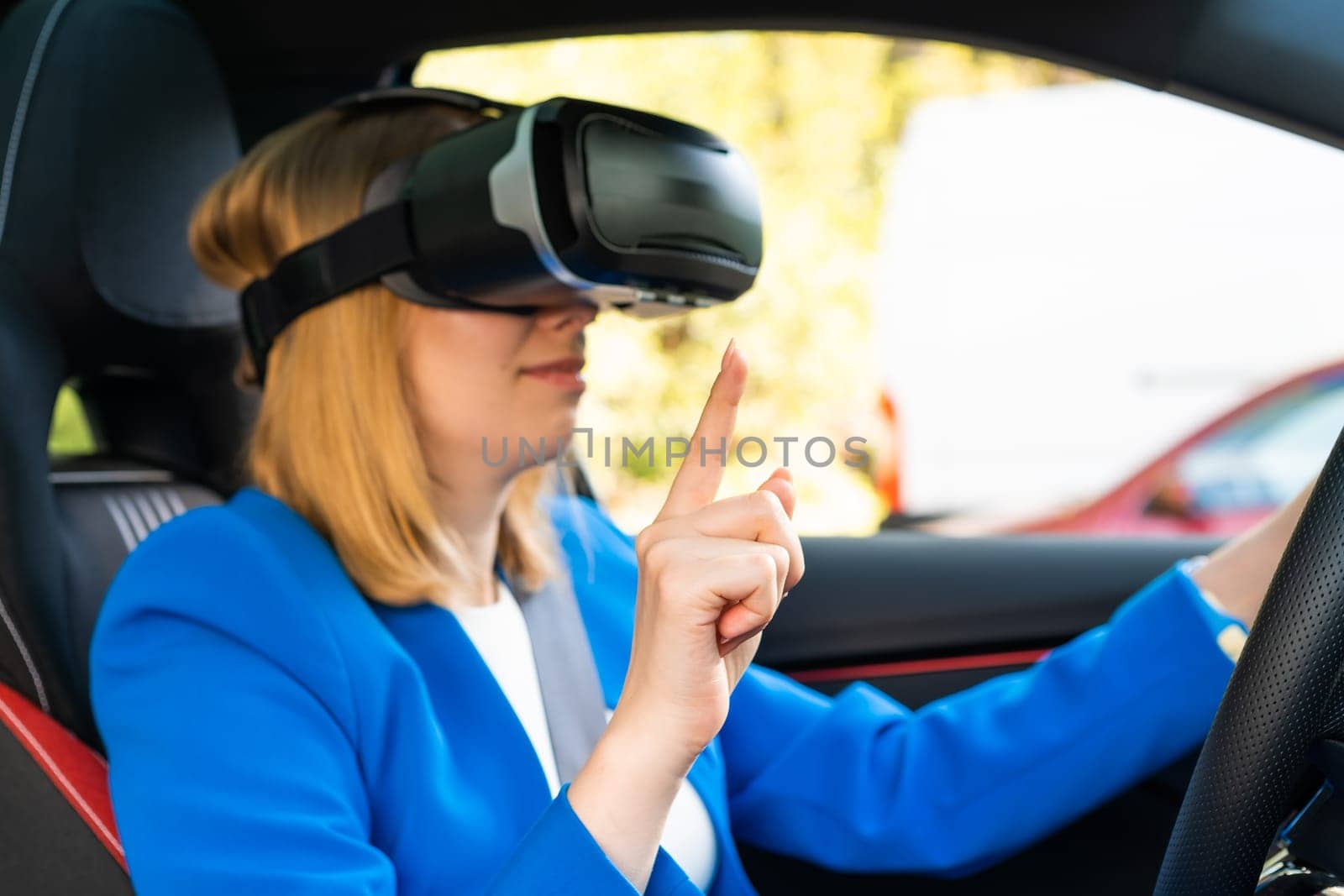 Businesswoman in the VR googles sitting in the car and turning the steering wheel in a car. Having and fun and playing games with augmented reality