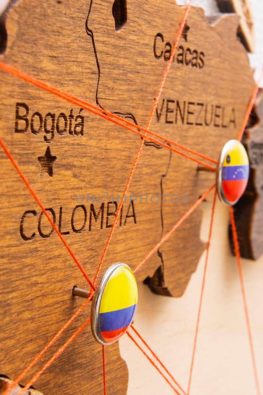 Colombia and Venezuela flags on the pushpin and red threads on the wooden map. Travel or logistic routes. Influence in geopolitics and world economy.