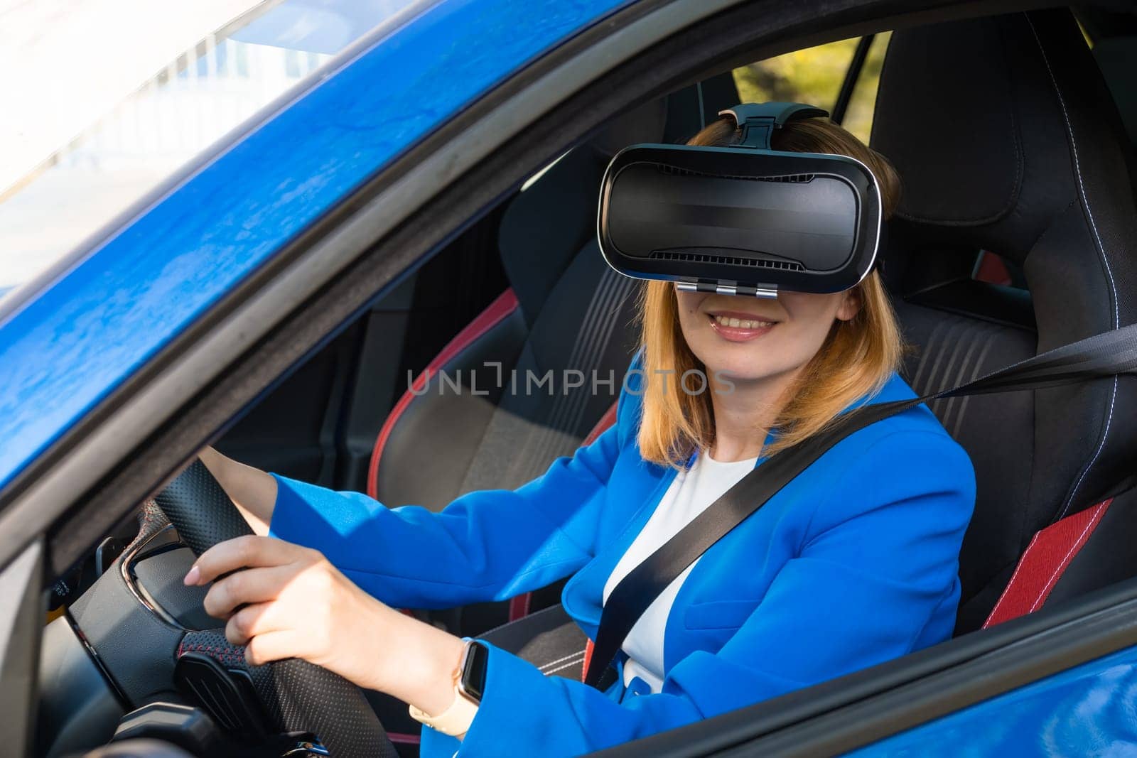 Smiling woman in the blue suit sitting in the car in VR goggles