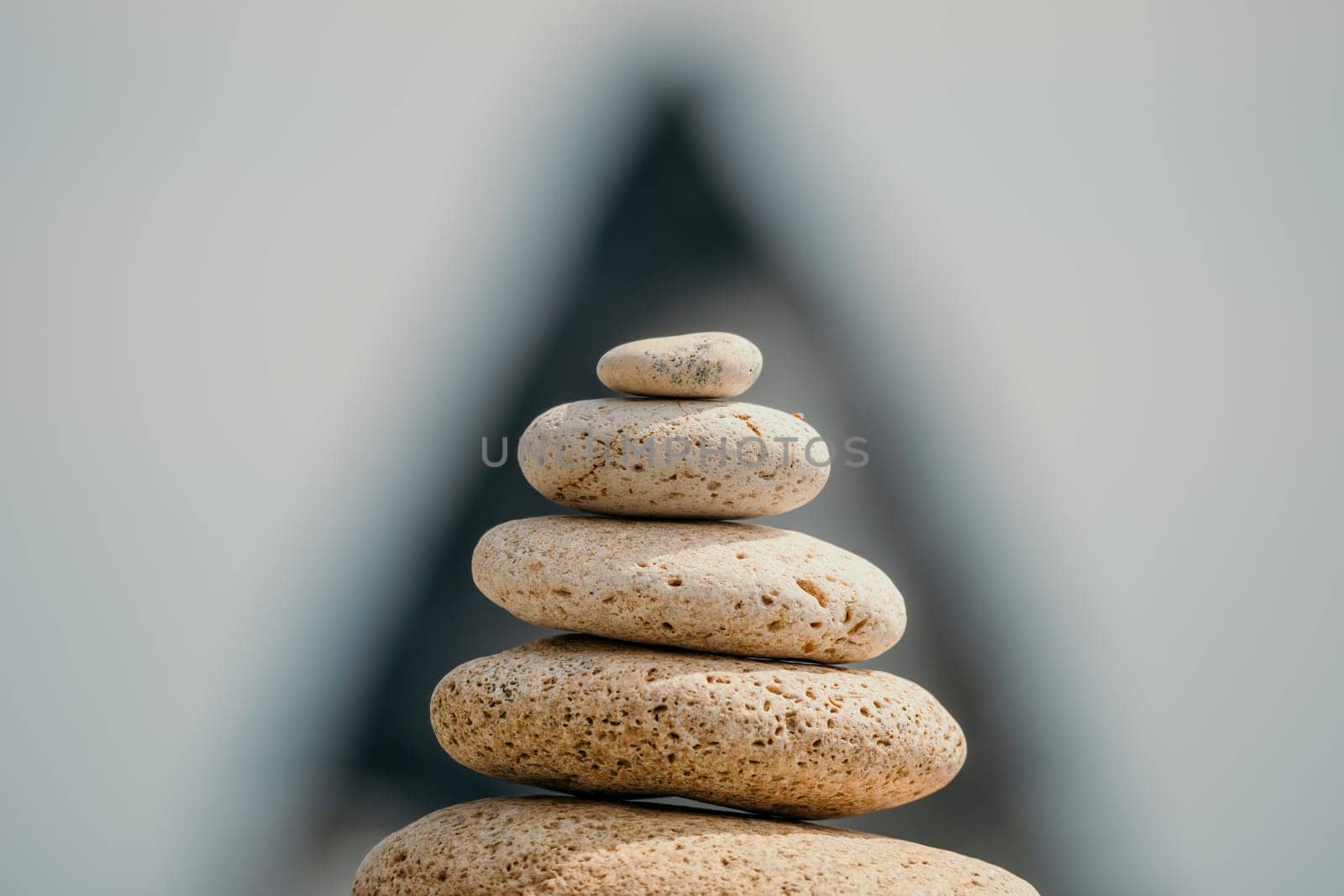 Pyramid stones on the seashore with warm sunset on the sea background. Happy holidays. Pebble beach, calm sea, travel destination. Concept of happy vacation on the sea, meditation, spa, calmness.