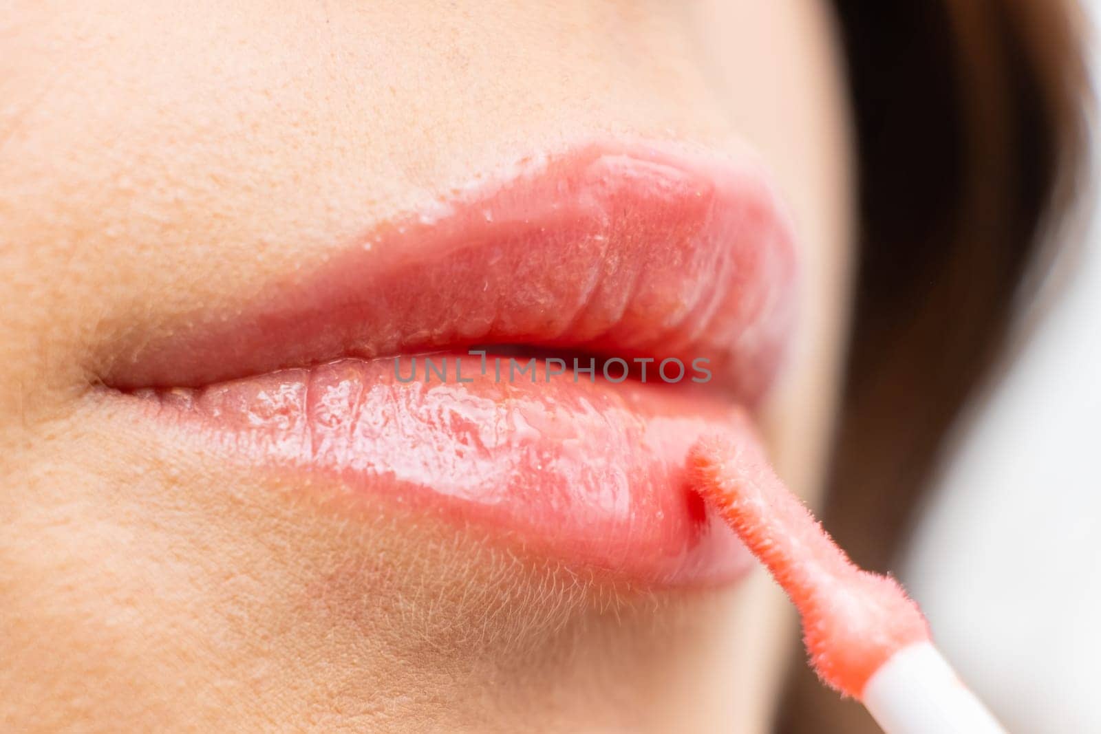 Applying lip gloss on the beautiful full lips by vladimka
