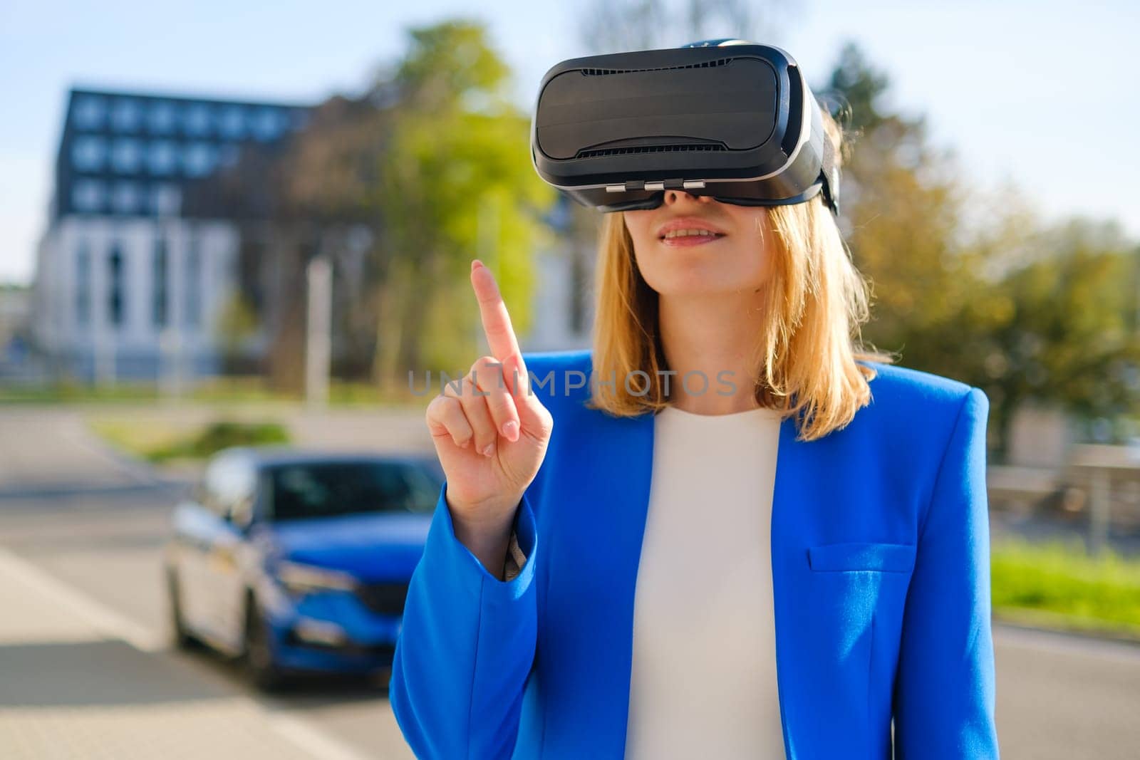 Business woman female wearing VR headset getting experience and managing interface in metaverse near business center, side view