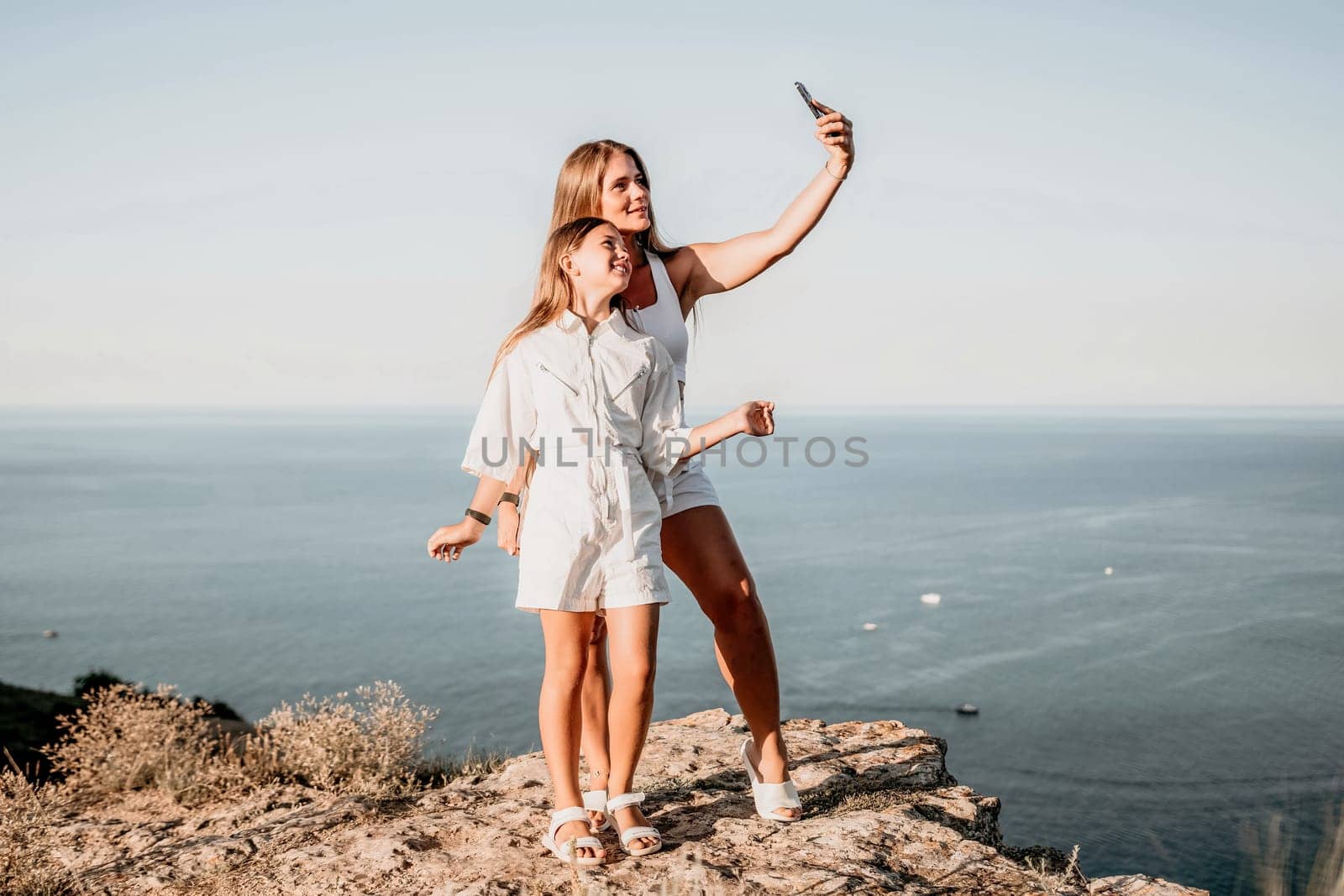 Woman travel sea. Young Happy woman in a long red dress posing on a beach near the sea on background of volcanic rocks, like in Iceland, sharing travel adventure journey