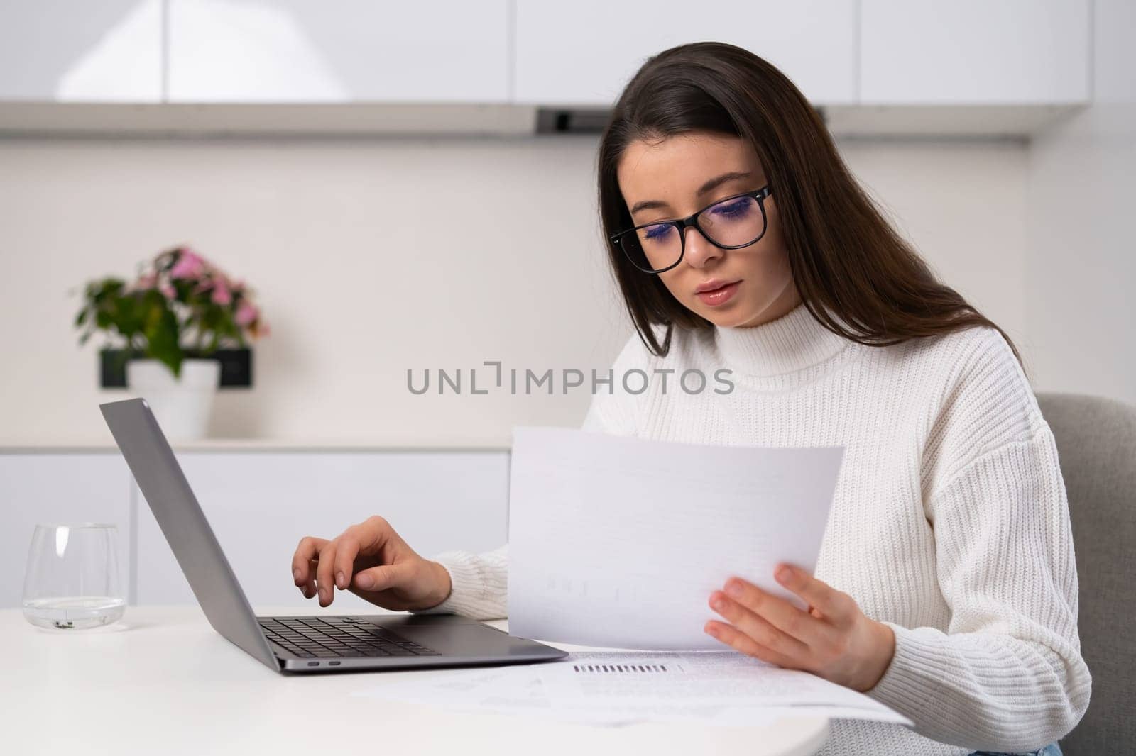 Focused woman enters data written in papers into Notebook by vladimka