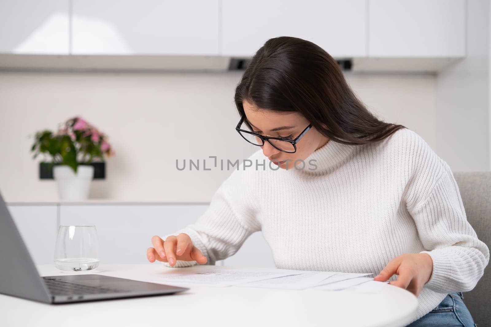 Beautiful young housewife checks bills with serious expression on her face.