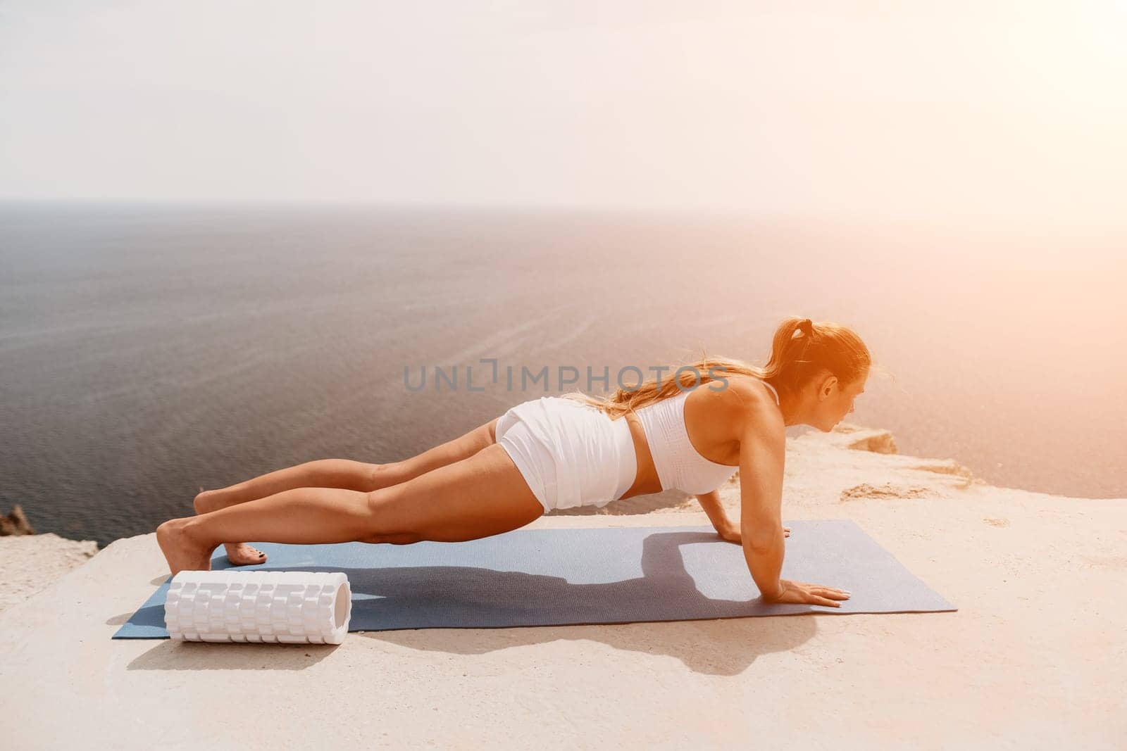 Woman sea pilates. Sporty middle-aged woman training in pilates on yoga mat by sea. concepts of health, wellness, and mindfulness in exercise, promoting the benefits of active and balanced lifestyle by panophotograph