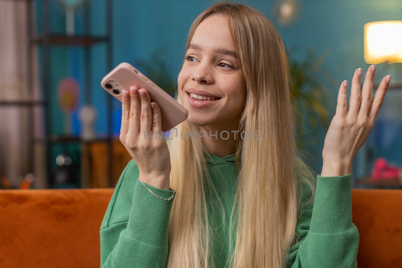 Happy excited woman making online phone call conversation with friends. Portrait of Caucasian girl enjoying mobile loudspeaker talking chatting communication at home apartment living room on couch