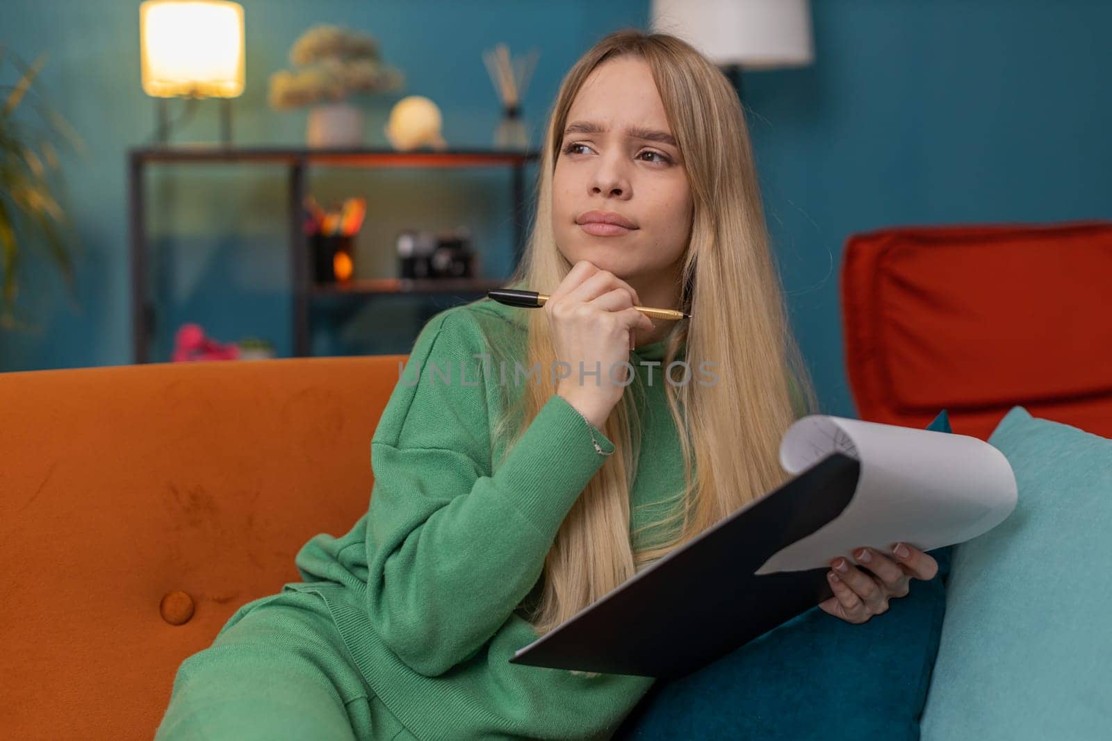 Caucasian woman freelancer work with documents on home couch, reading information, business papers prepare financial report on laptop. Young girl accountant analyzing graph documents, calculate taxes