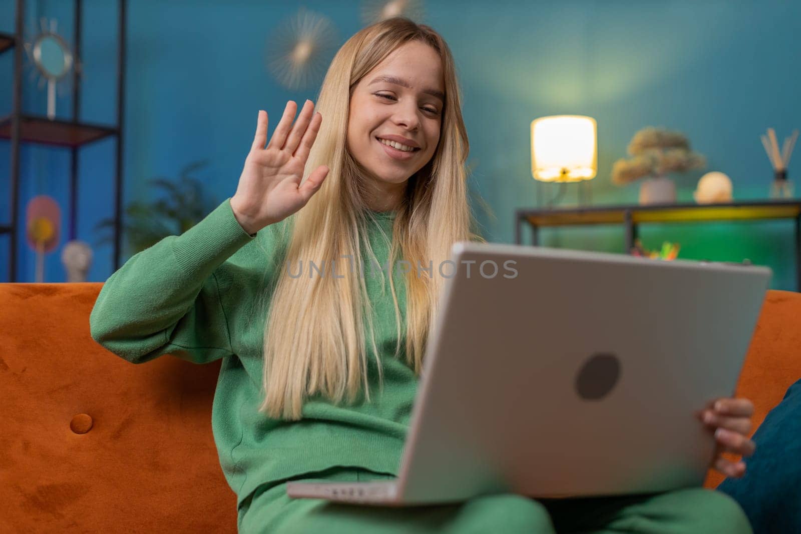 Caucasian woman sitting on couch looking at camera, making video webcam conference call with friends or family, enjoying pleasant conversation. Young girl laughing waving hello at home room apartment