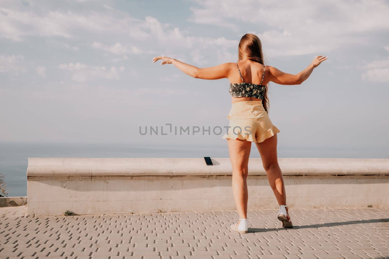 Woman summer dance. Silhouette of a happy woman who dances, spins and raises her hands to the sky. A playful young woman enjoys her happy moment dancing in the rays of the golden sun. by panophotograph