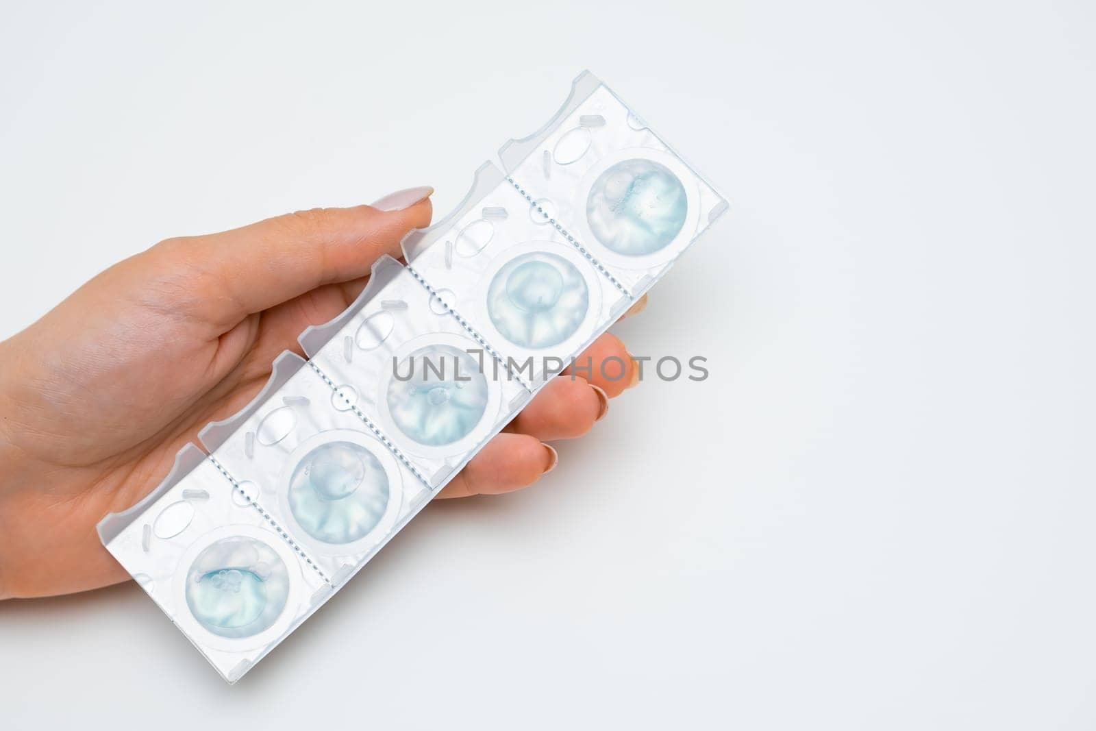 Blister with disposal contact lenses in womans hands on the white background.